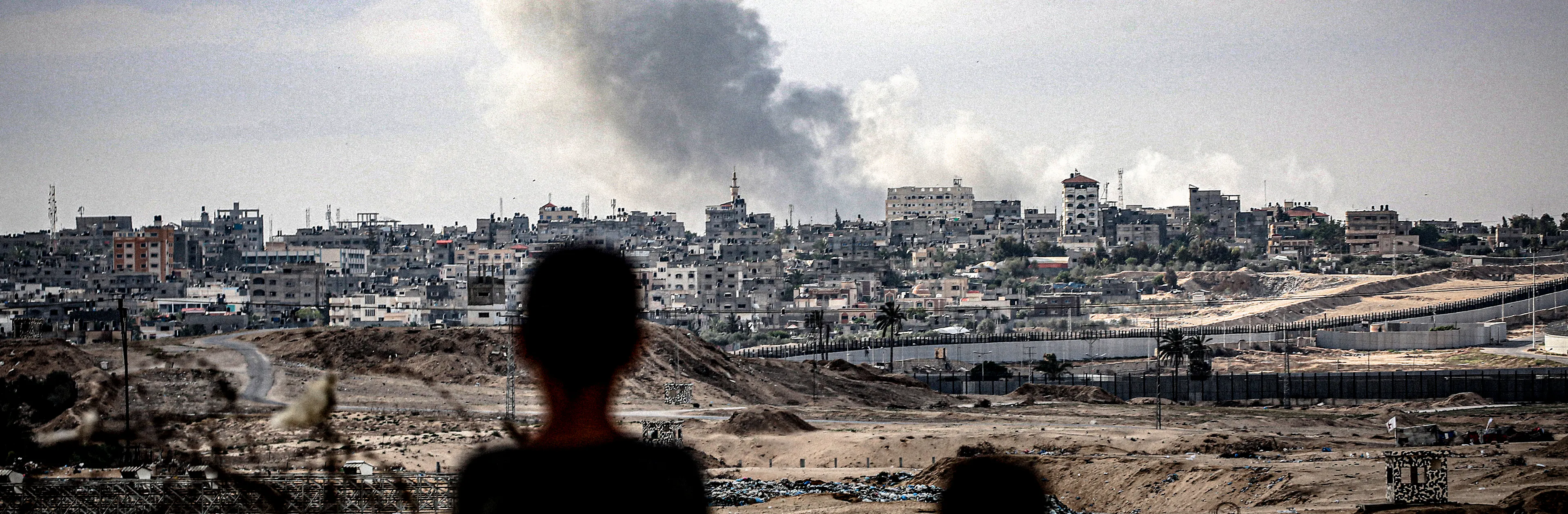 Two children from Rafah, south of the Gaza Strip, watch plumes of smoke rise after an airstrike hit at the center of the city. 