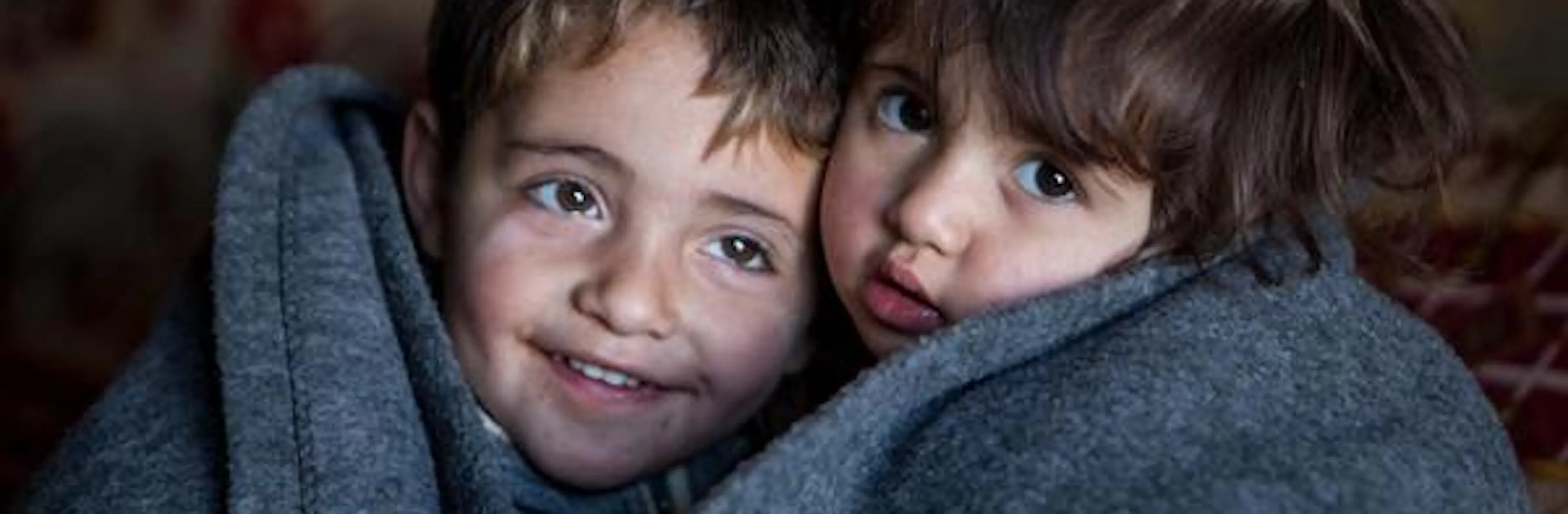 Hakim and Amira wrapped up in blanked inside the family tent in the Domiz refugee camp in Northern Iraq.