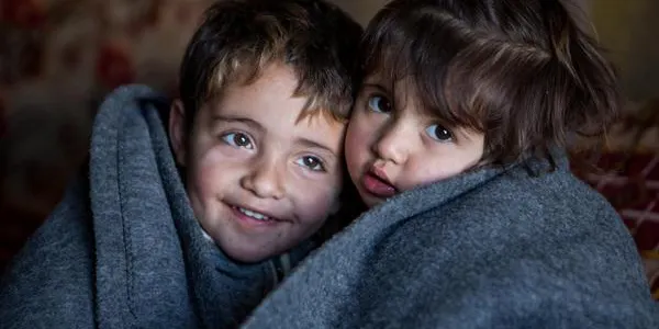 Hakim and Amira wrapped up in blanked inside the family tent in the Domiz refugee camp in Northern Iraq.