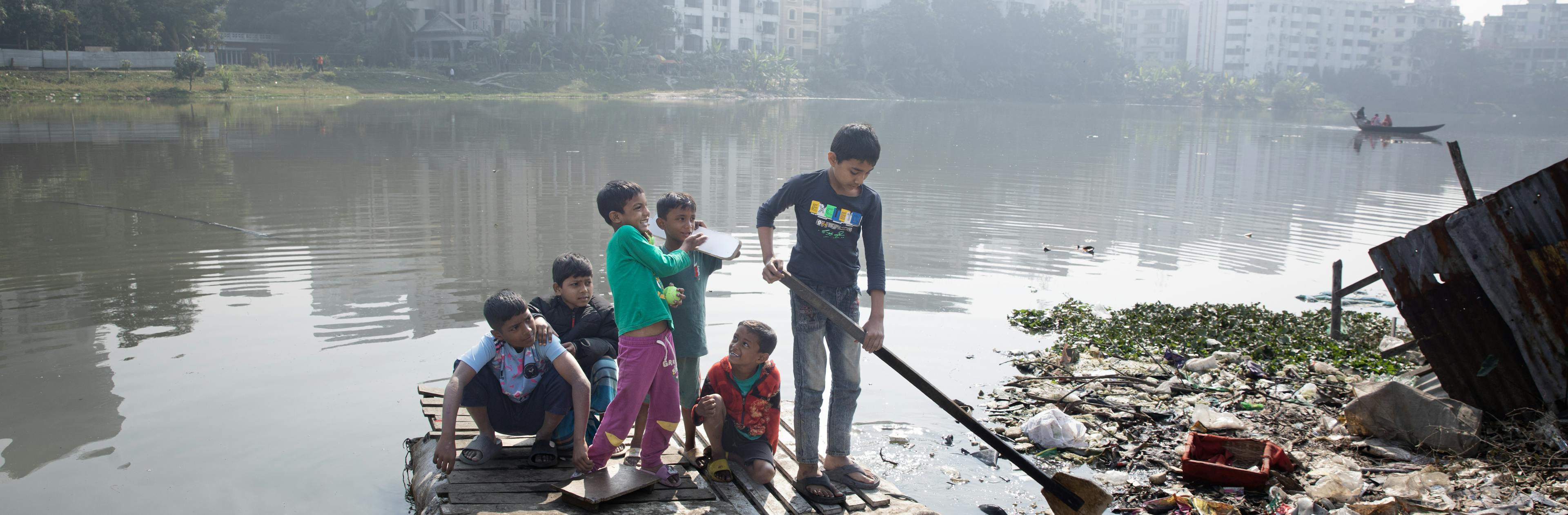 Children are having fun on a raft, after winning their cricket match, on the polluted Banani Lake in the Korail Slum of Dhaka, Bangladesh, on 28 January 2024
