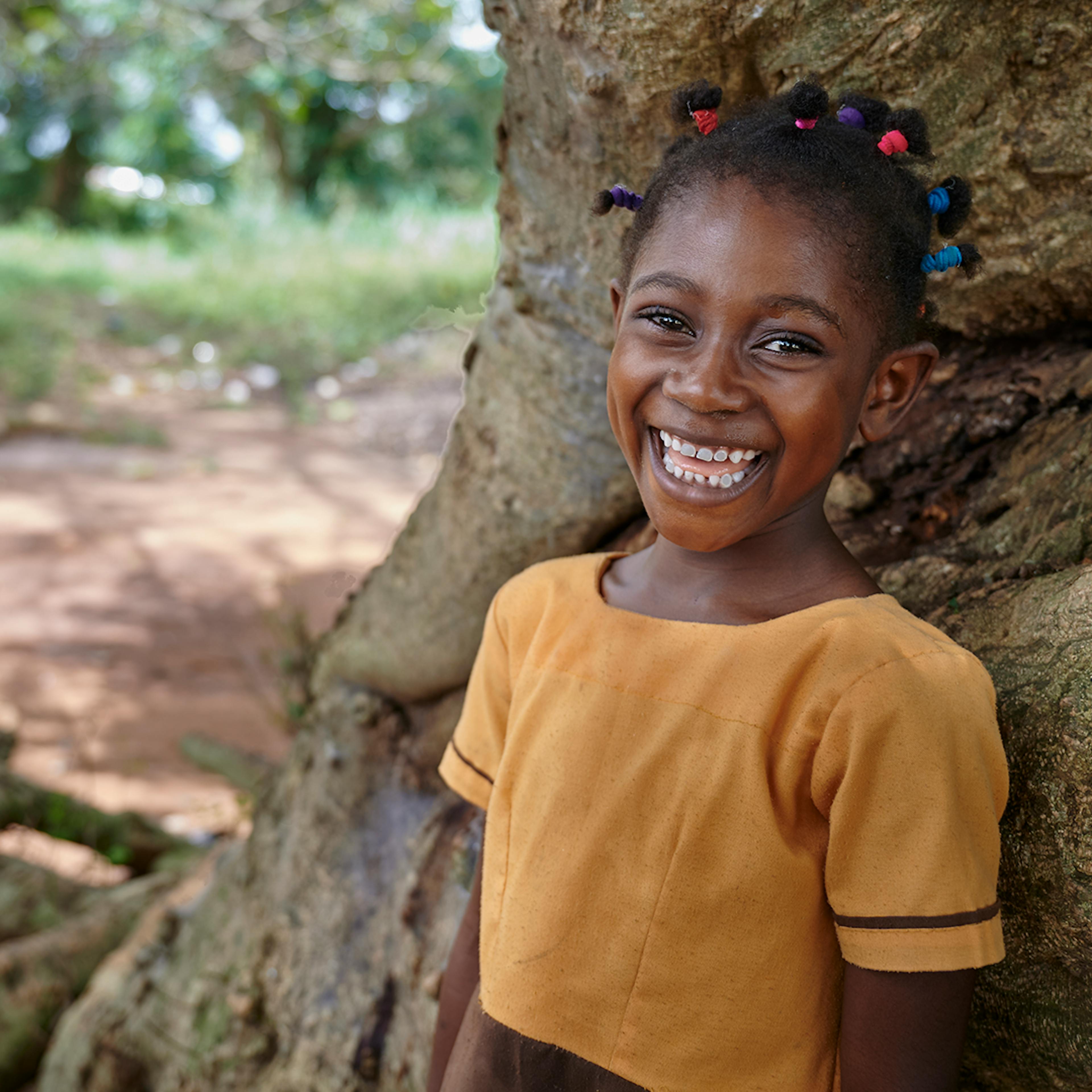 Maybe smiles standing by a tree during a break at Owusu Forkuo Junior High School in Juaben Municipality of Ashanti Region in Ghana. West Africa.