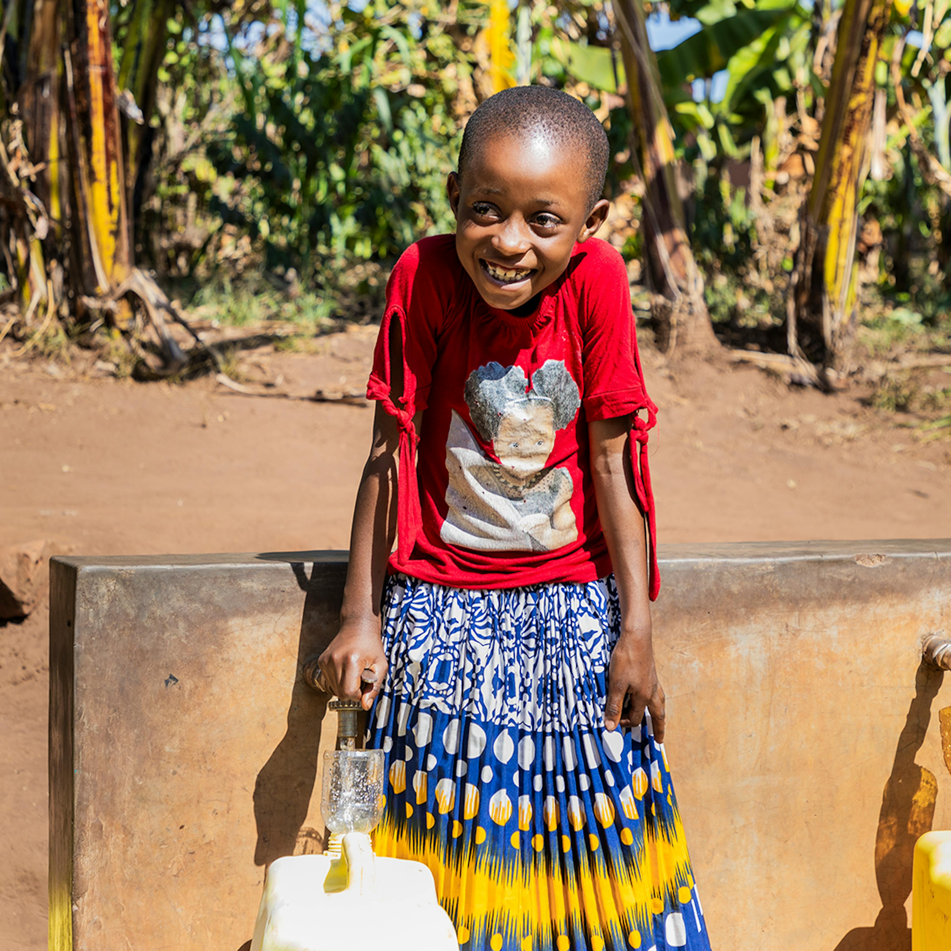 On 17 July 2023, 8-year-old Bonette fills water containers from taps that are part of a solar-powered water supply system in her neighbourhood in Kigarama Sector, Kirehe District, Eastern Province of Rwanda. Bonette is photographed during a visit by UNICEF Goodwill Ambasador Vanessa Nakate.