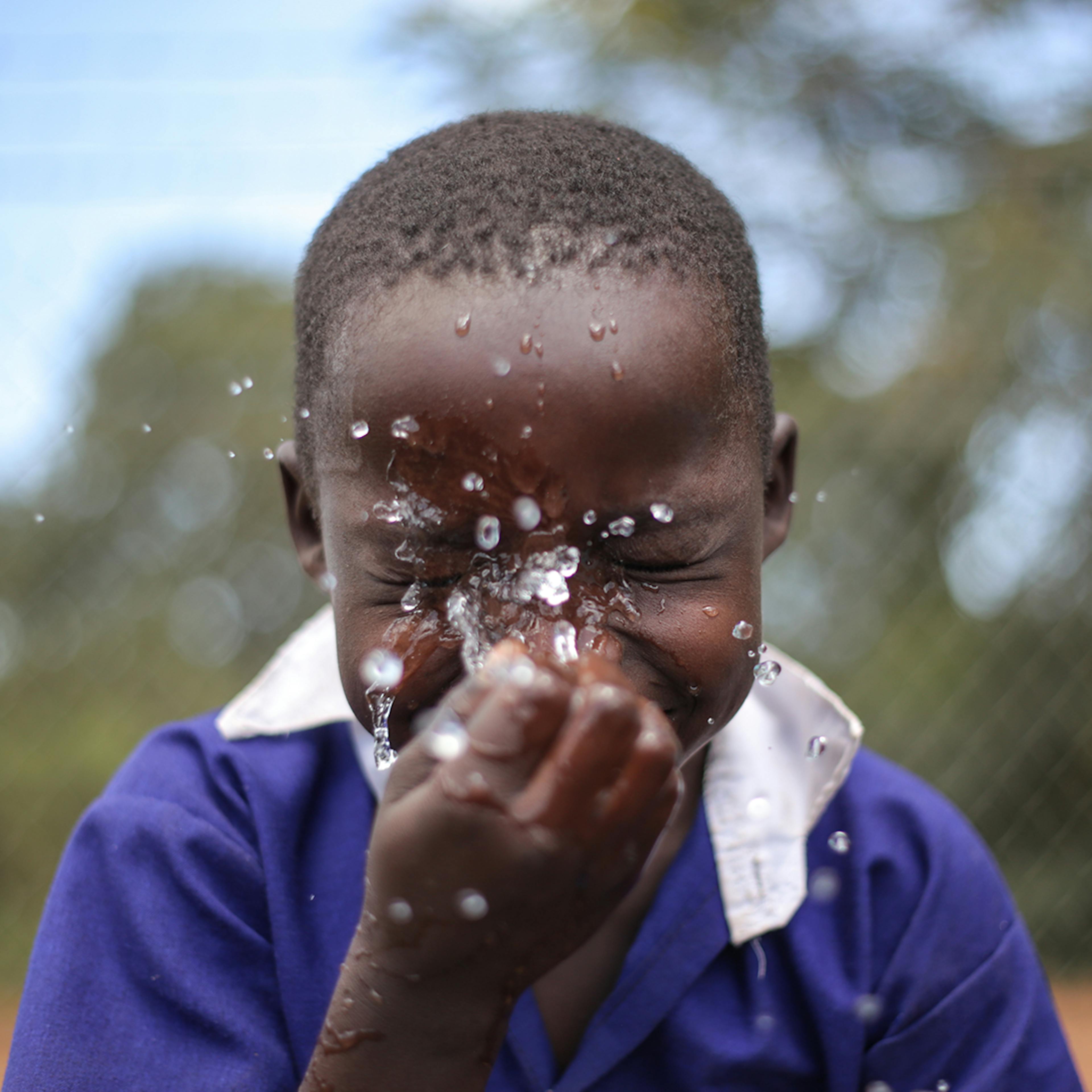 Collin Agwang, 8, a pupil of Orwamuge Primary School in Abim District splashes his face with water from a tap at the school after drinking some on 23 September 2022. 