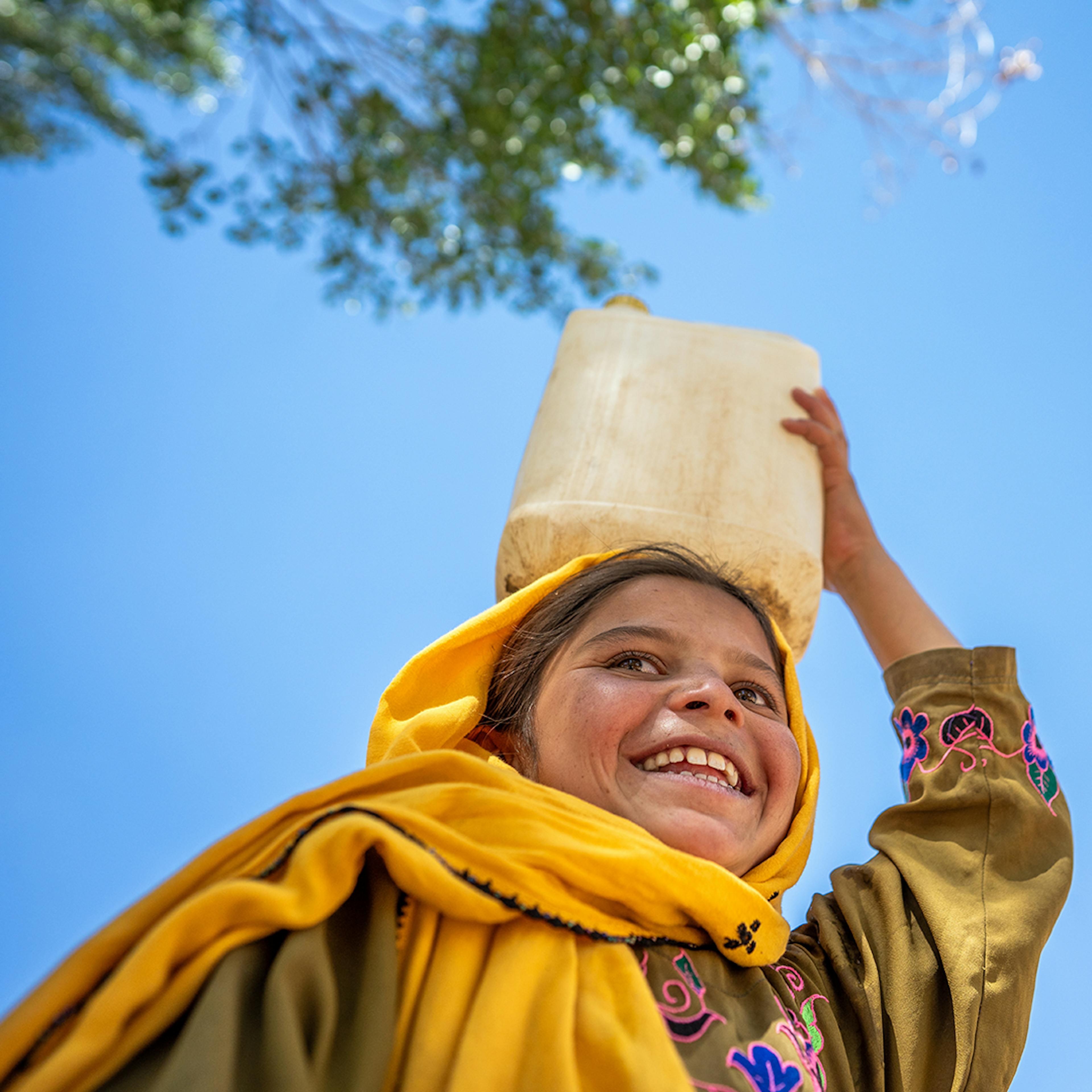 On the 28th May 2024, a girl carries a jerry can of water - provided by UNICEF - through her village in Chaghcharan district, Ghor province in western Afghanistan.