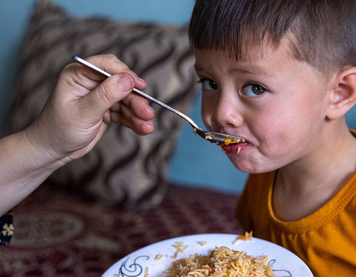 Mokhtar, 4 years old, eats a meal at home in Mazar, northern Afghanistan. His mother, Zahra, has mixed UNICEF-supplied micronutrient powders inside the food.