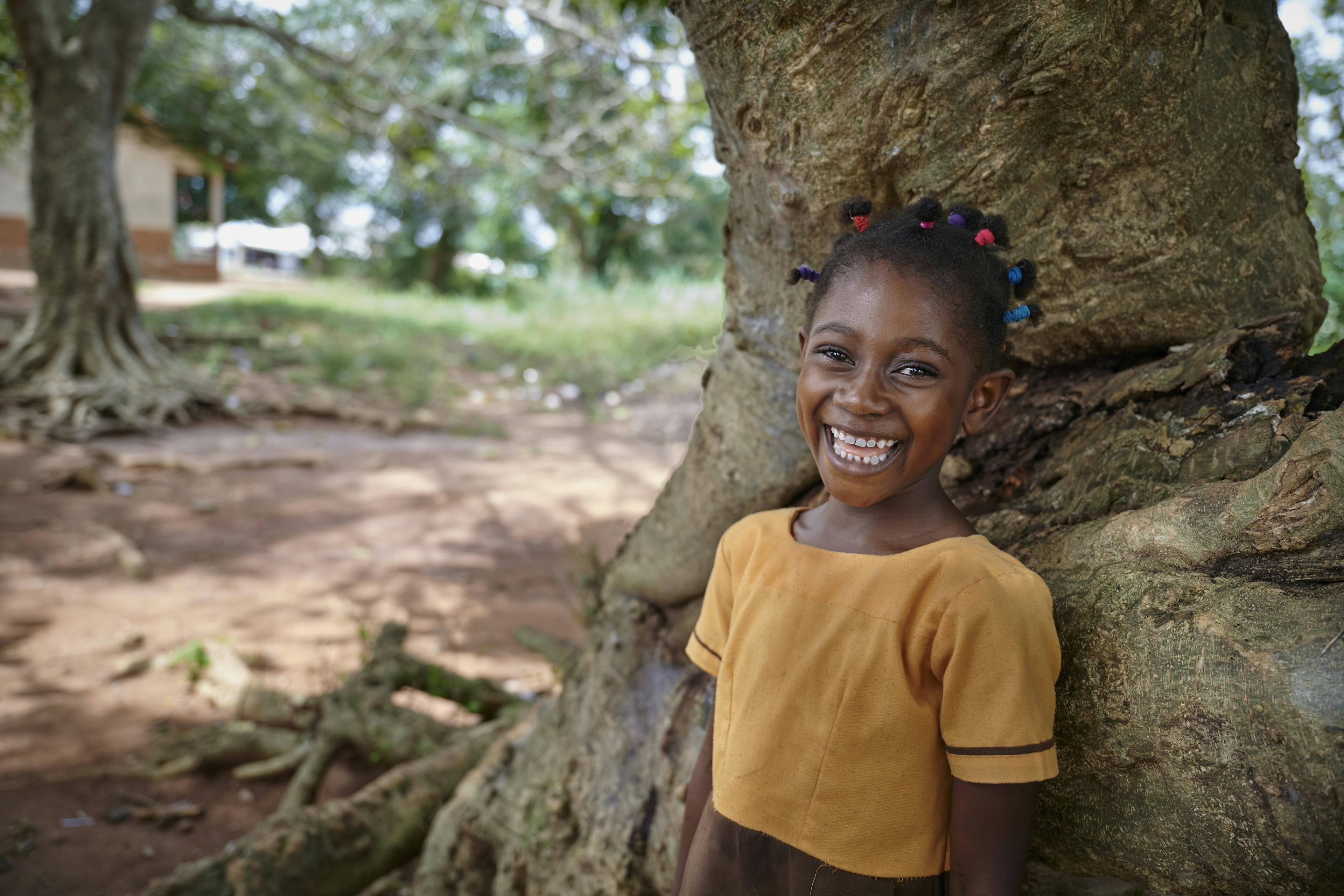 Maybe smiles standing by a tree during a break at Owusu Forkuo Junior High School in Juaben Municipality of Ashanti Region in Ghana. West Africa.