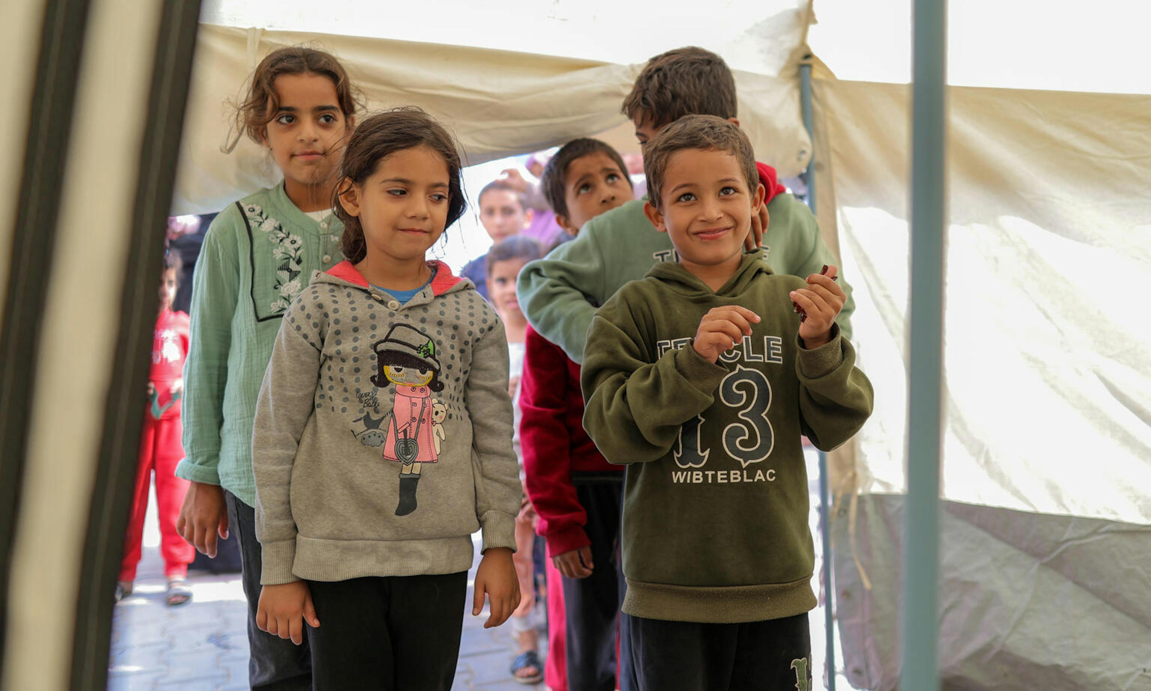 Boy and girl in Gaza standing at the front of a line with other kids lined up behind them.