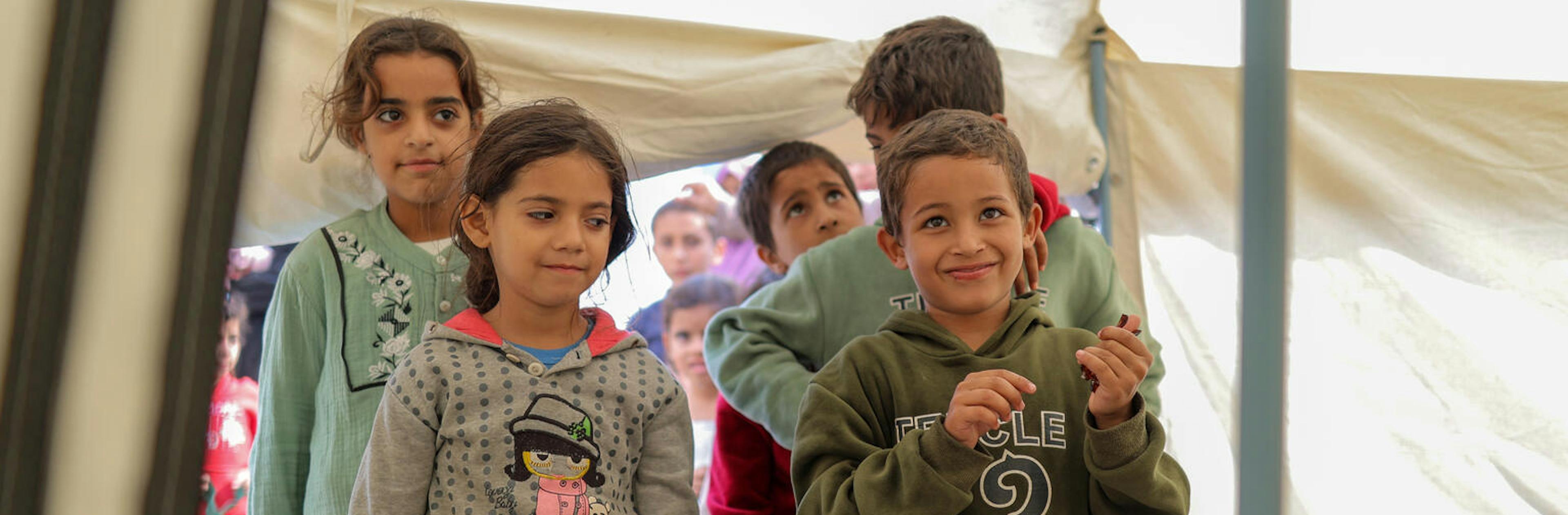 Boy and girl standing at the front of a line with other kids lined u behind them.