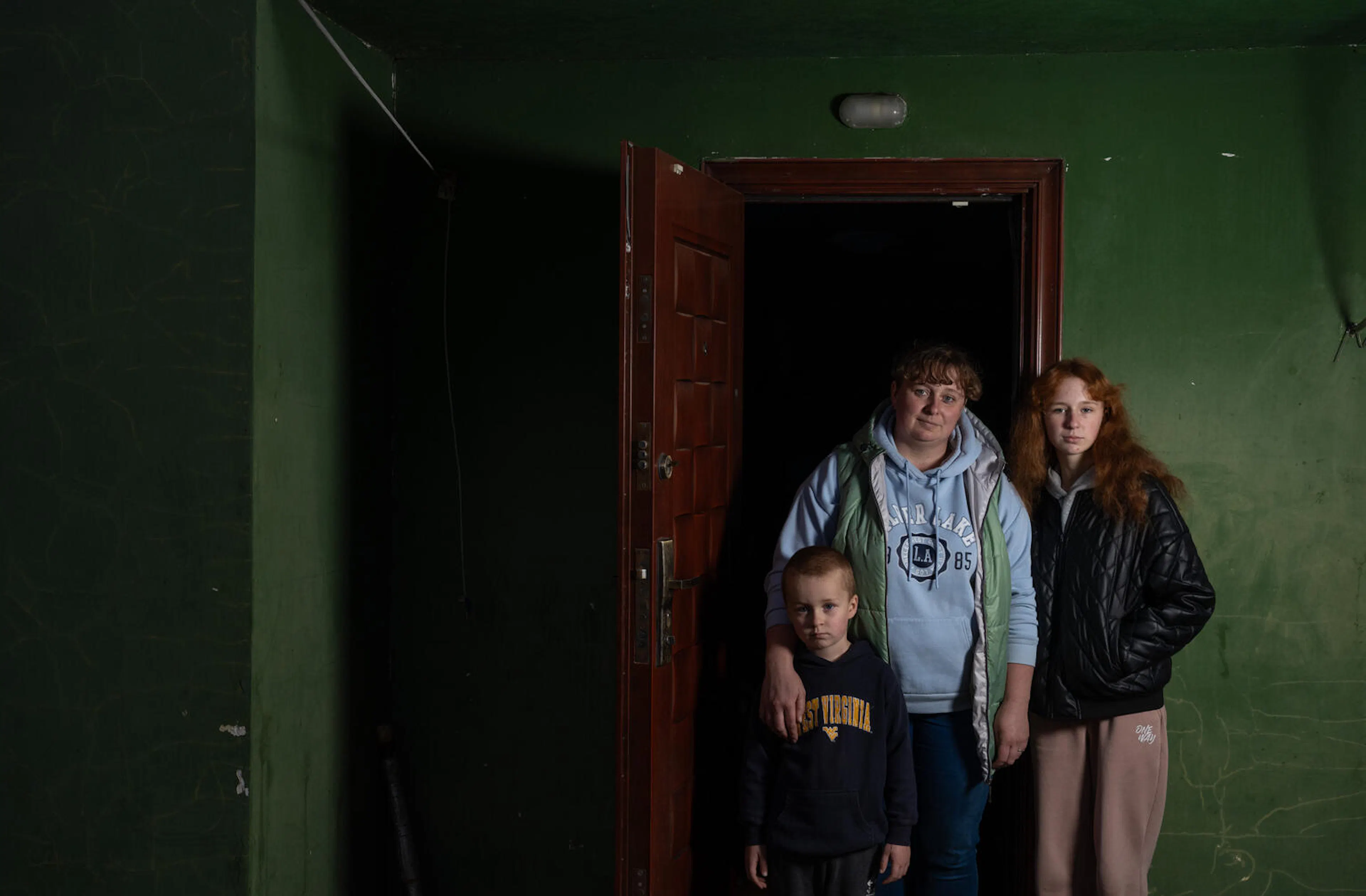 Katya stands with her five-year-old son, Andriy, and 14-year-old daughter, Halyna, outside their rented home in Khotimlya, Kharkiv region.
