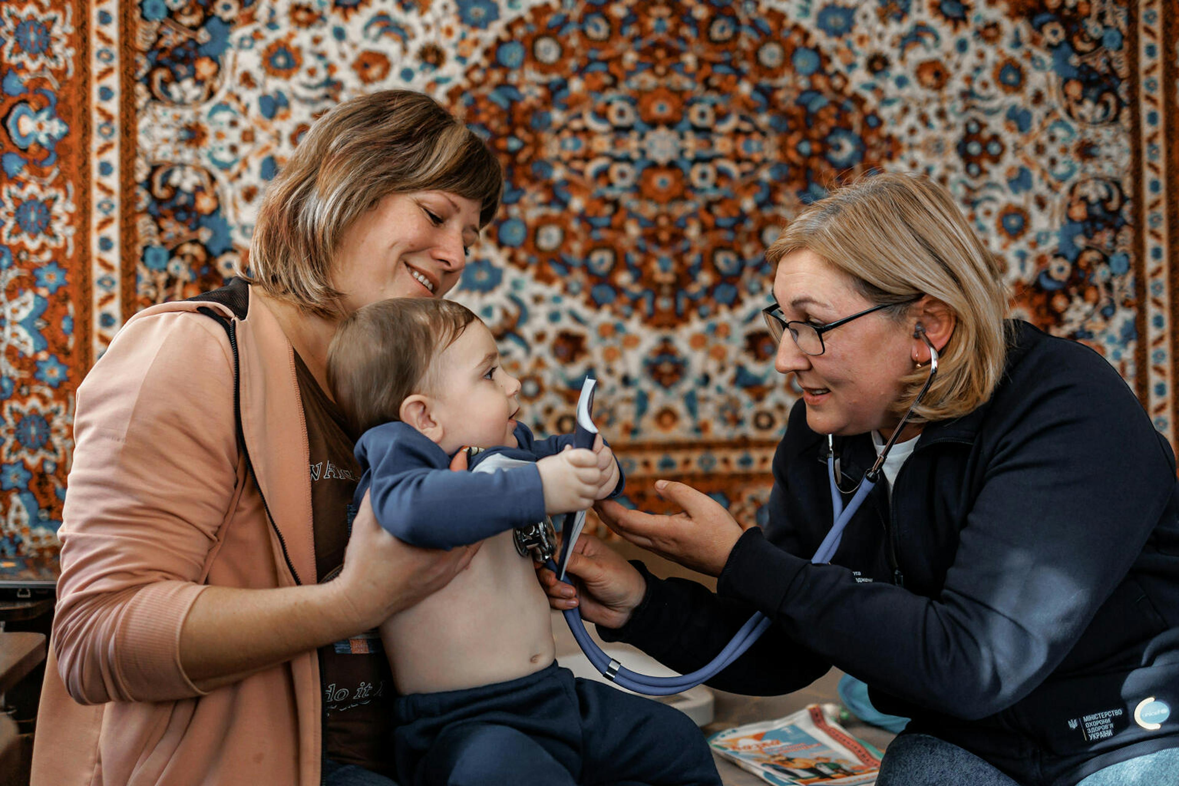 Nurse Svitlana Kuts conducts a health check-up for 10-month-old Daniil during a home visit, 