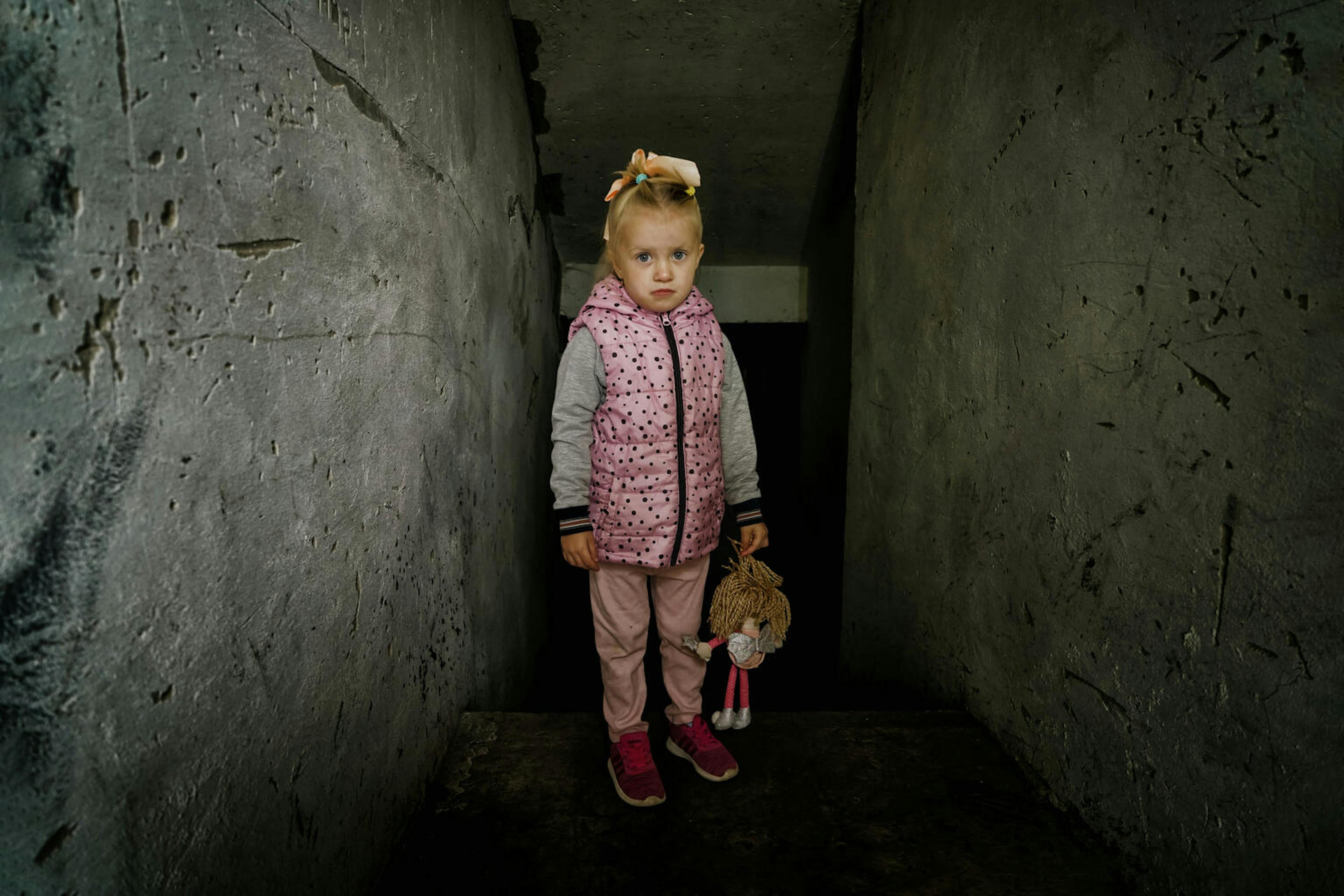 Milana, four years old, stands in front of the destroyed boiler room at her kindergarten.