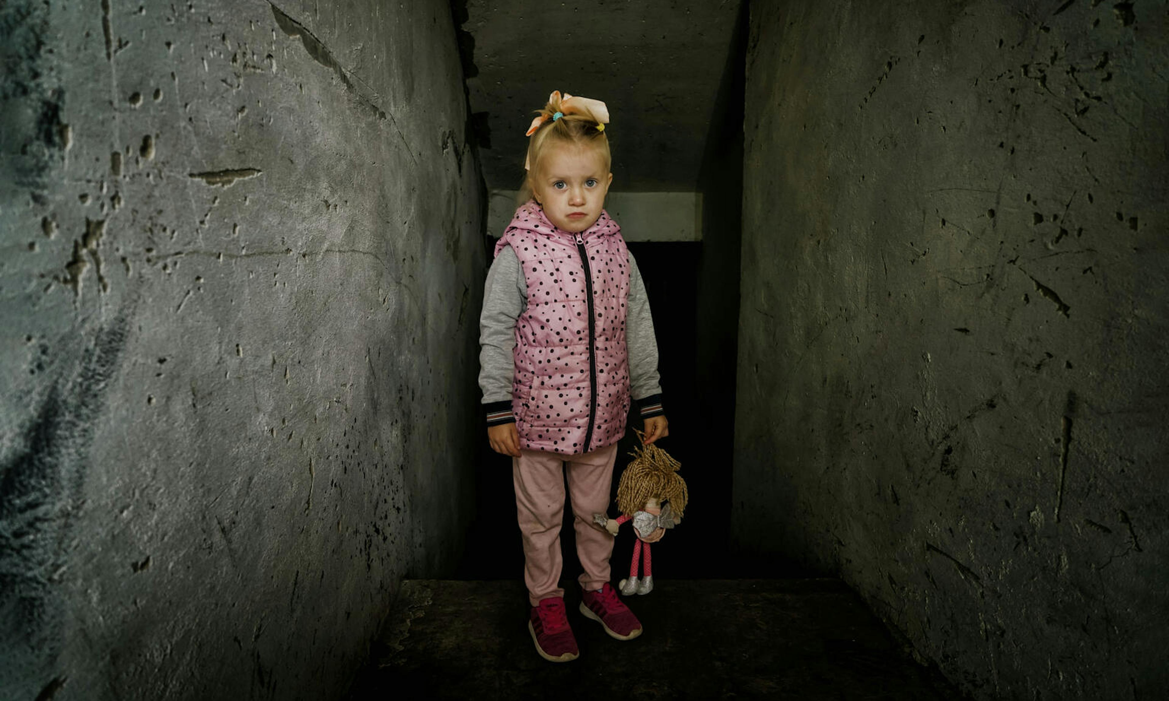 Milana, four years old, stands in front of the destroyed boiler room at her kindergarten.