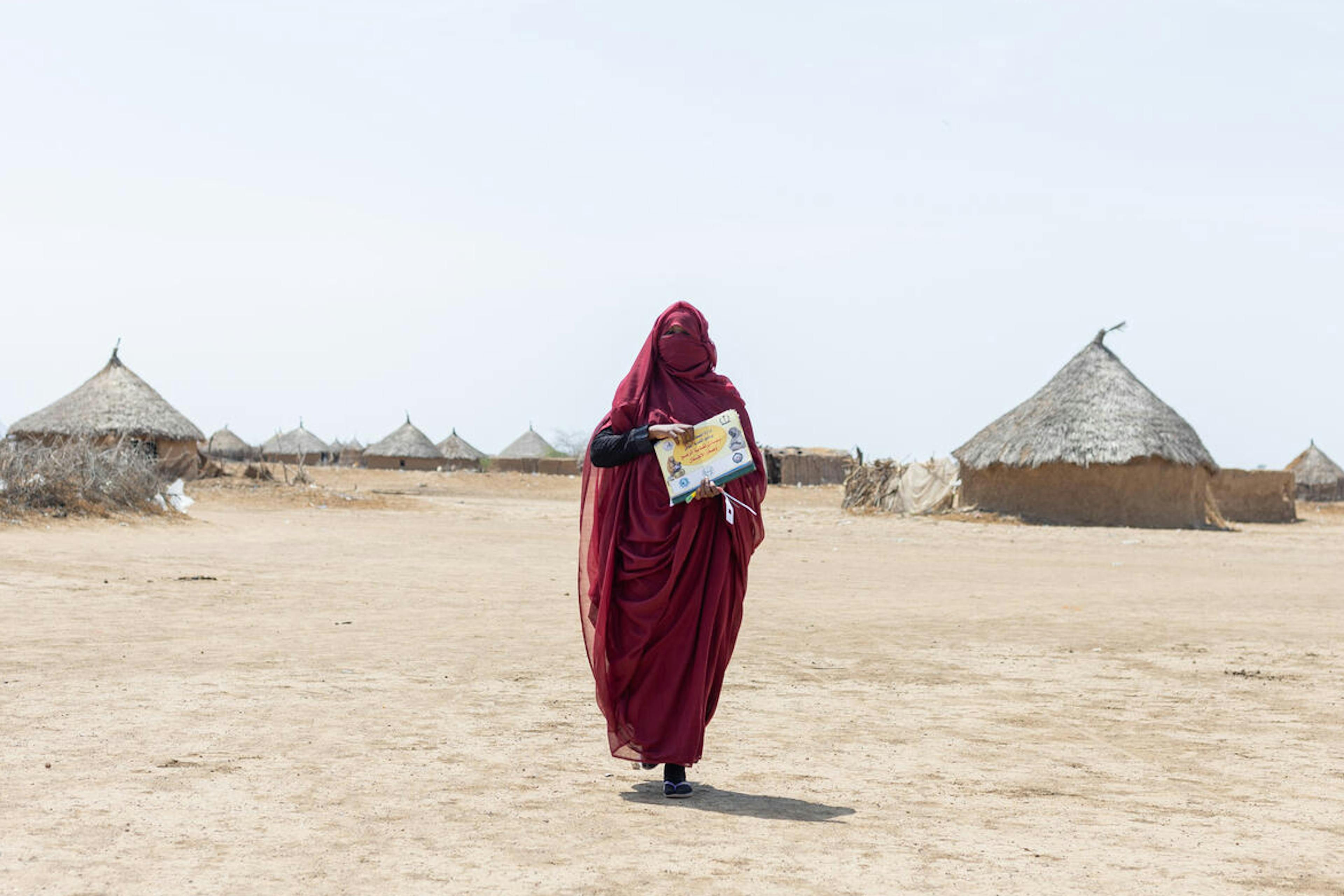 Sudan woman walking through a rural area to a local village