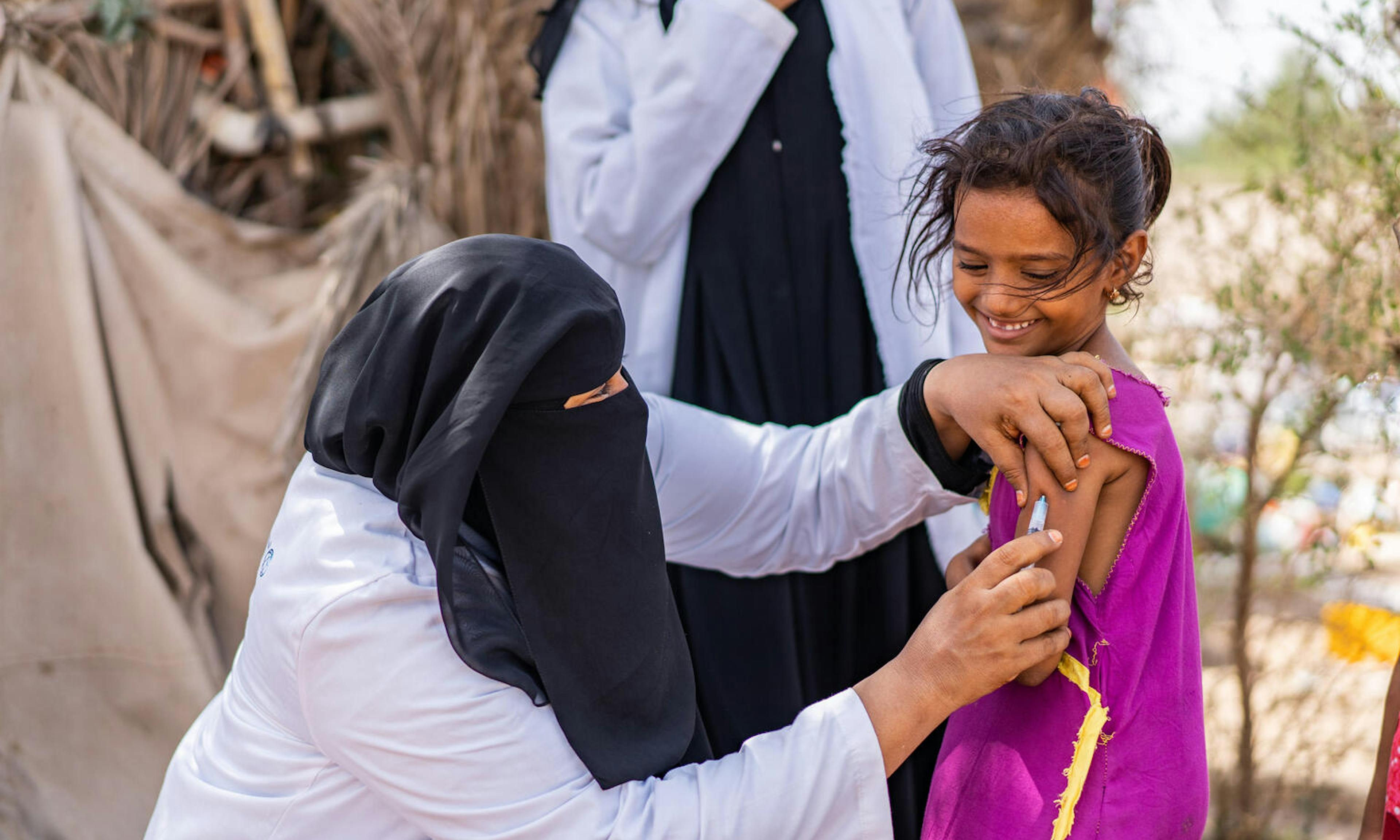 Health worker Ghada Ali Obaid, 53, vaccinates 9-year-old Aswar Saddiq Othman during a community outreach vaccination drive for children.