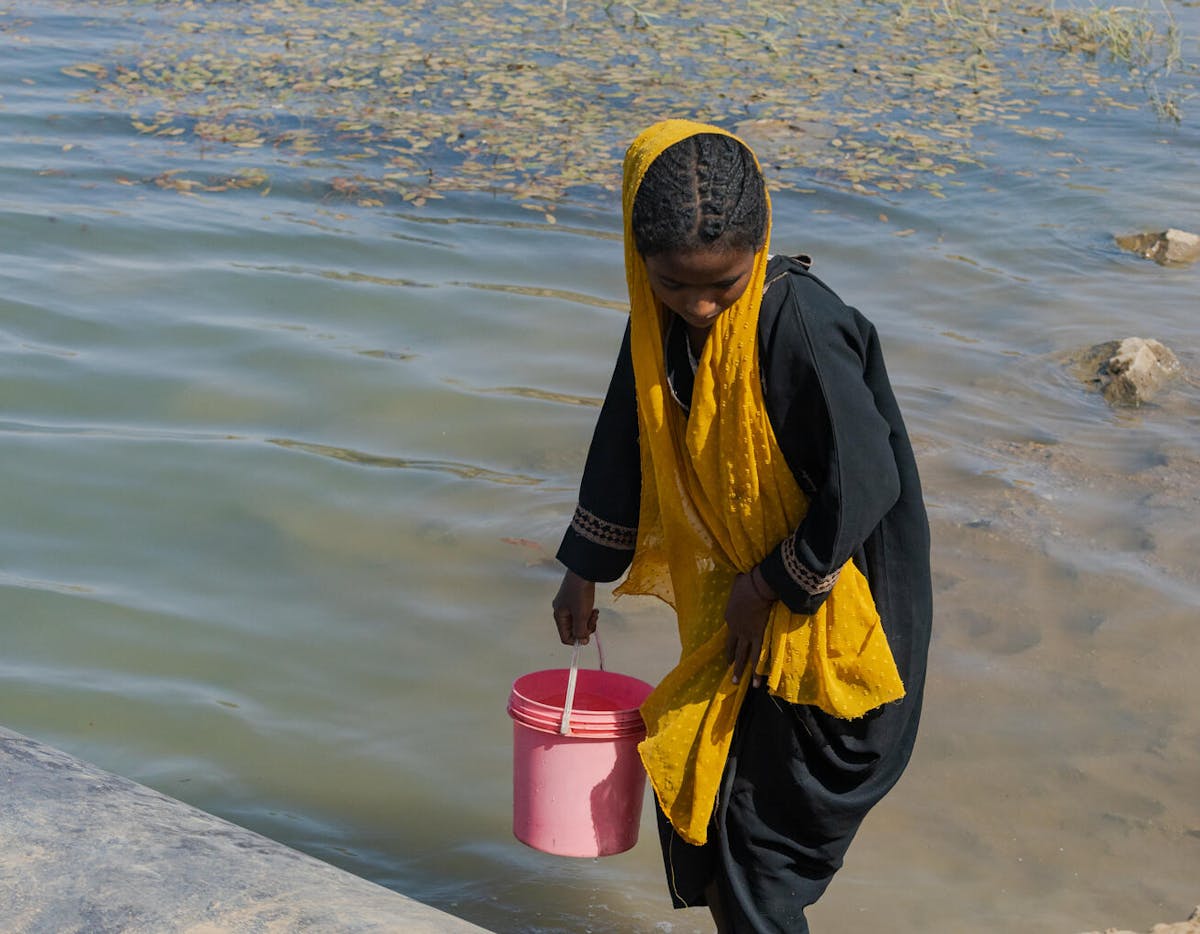 12-year-old Shaimaa descends to the canal to demonstrate how she collected water in the past. The water source was shared with animals.