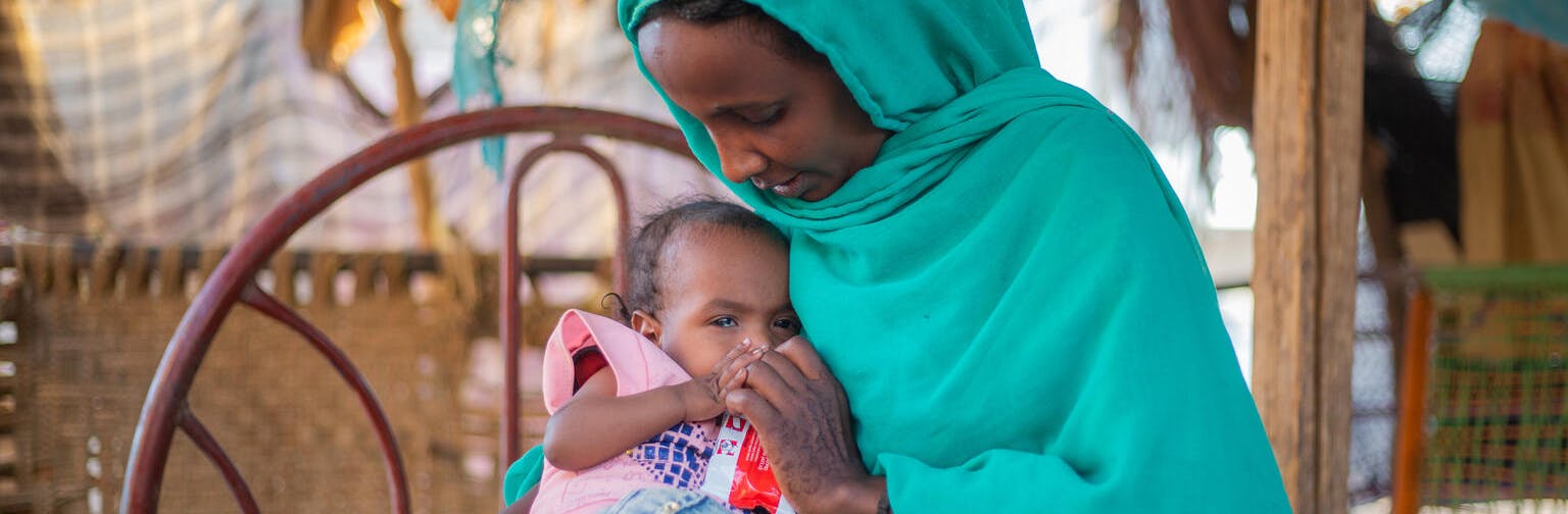 Woman feeds child ready-to-use therapeutic food