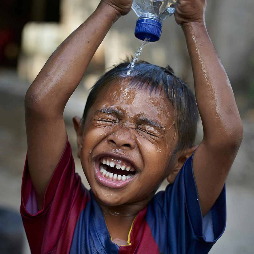 A young child splashes water on his face