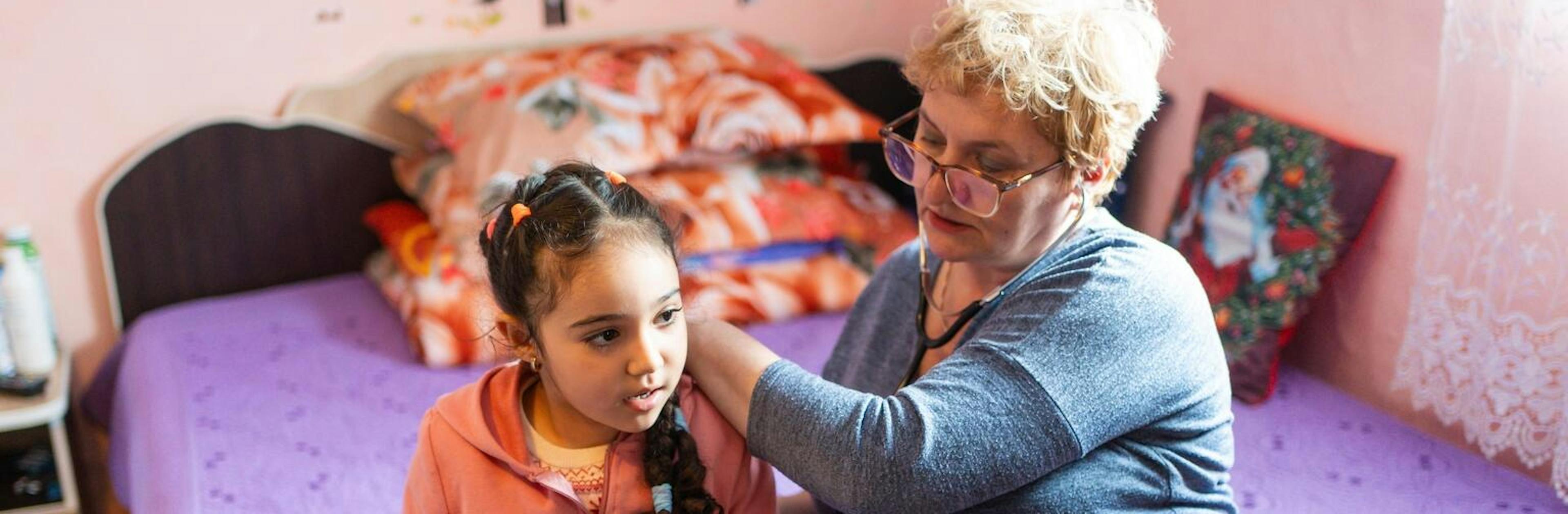 Woman listens to child's heart through stethoscope