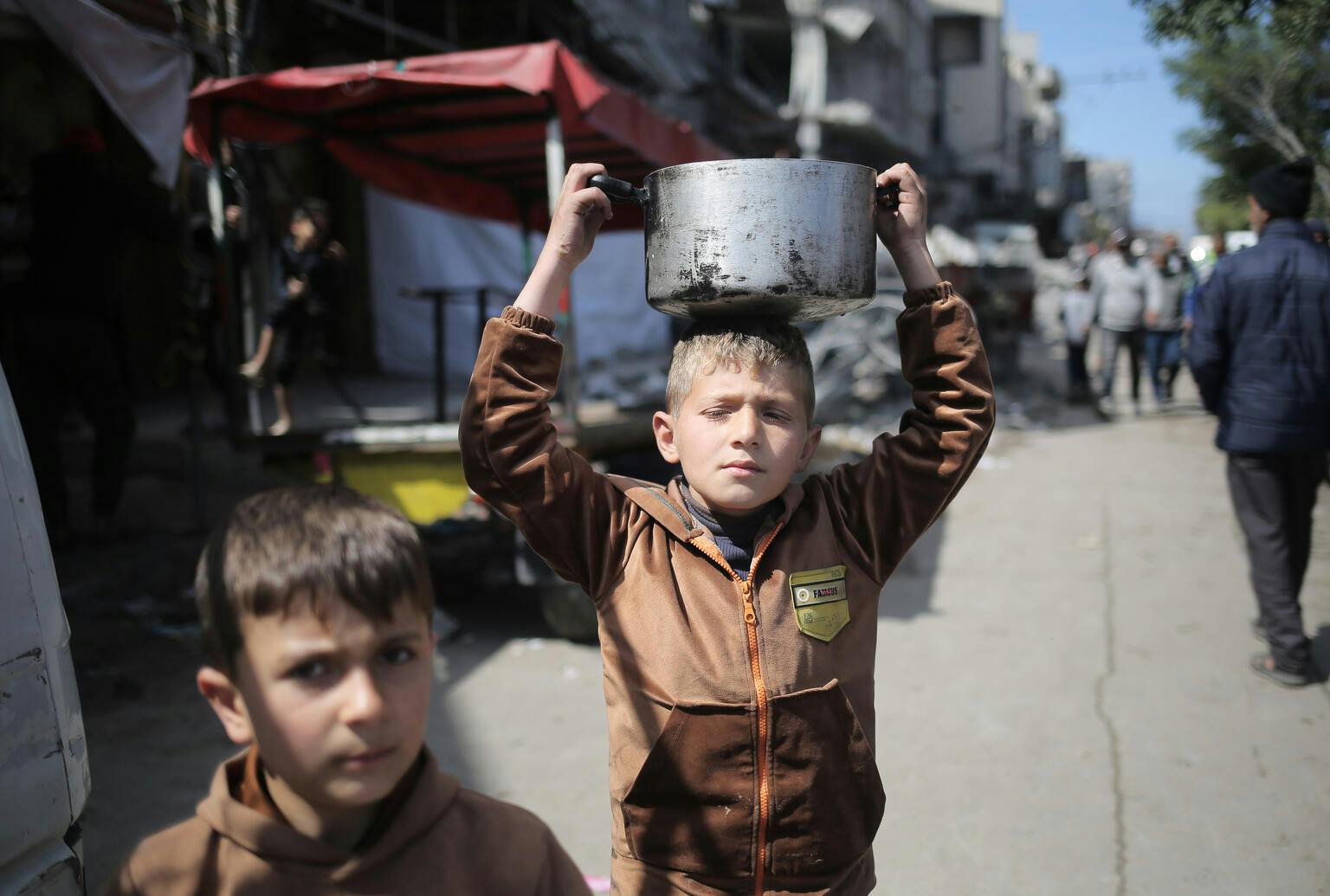 9-year-old Fadi walks the street while holding a pot of food on his head in Rafah, southern the Gaza Strip
