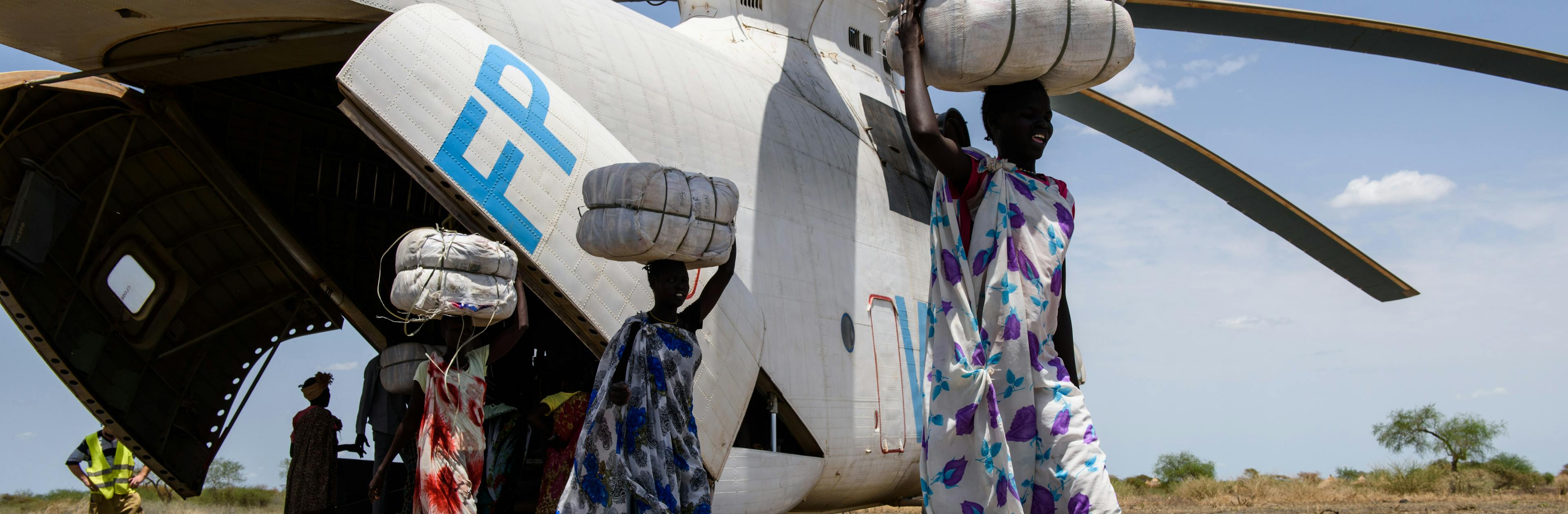 Porters carry bales of mosquito nets from a helicopter during a Rapid Response Mission in the village of Aburoc, South Sudan