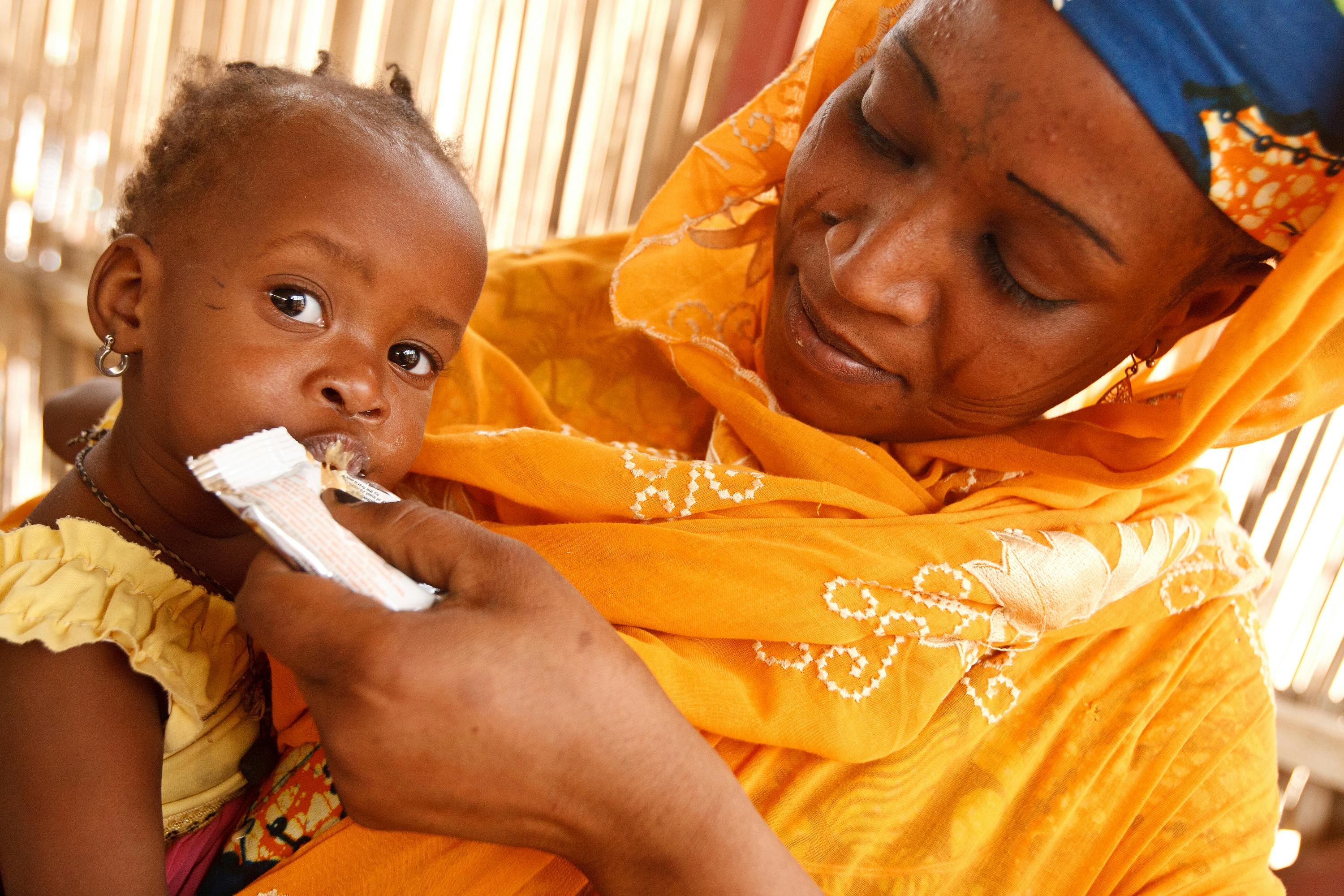 A woman feeds ready-to-use therapeutic food to her malnourished daughter, at the UNICEF-supported Routgouna Health Centre, in the town of Mirriah, Mirriah Department, Zinder Region.