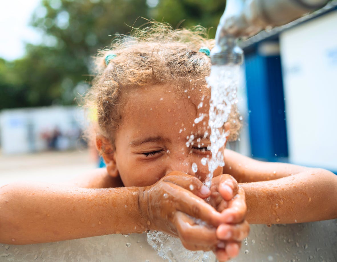 Judith Qiñonez drinks water from a UNICEF-supported water tap.