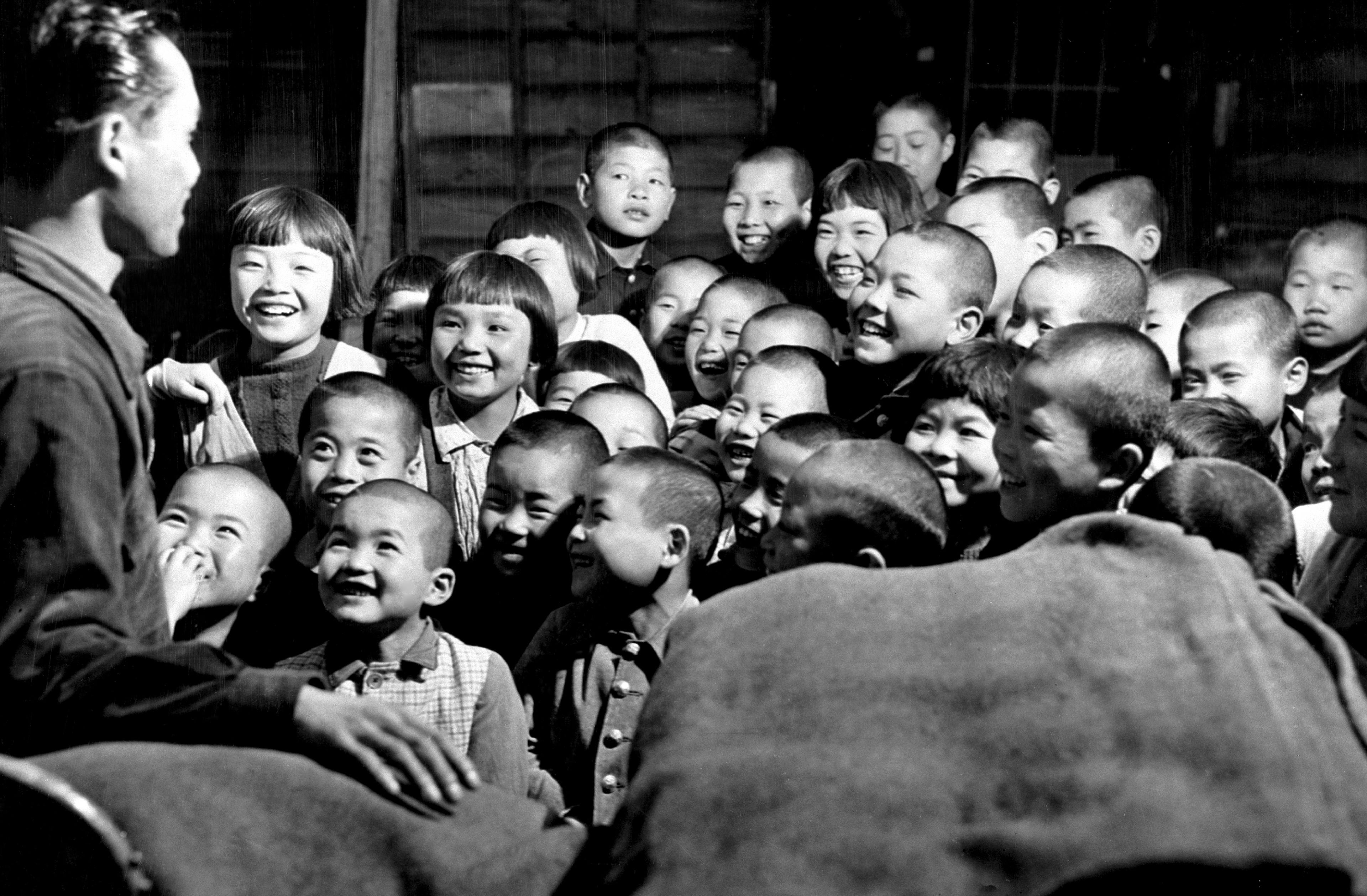 Children from disaster-stricken families affected by typhoons in the city of Saga, Japan smile as they wait to receive blankets supplied with UNICEF's assistance.