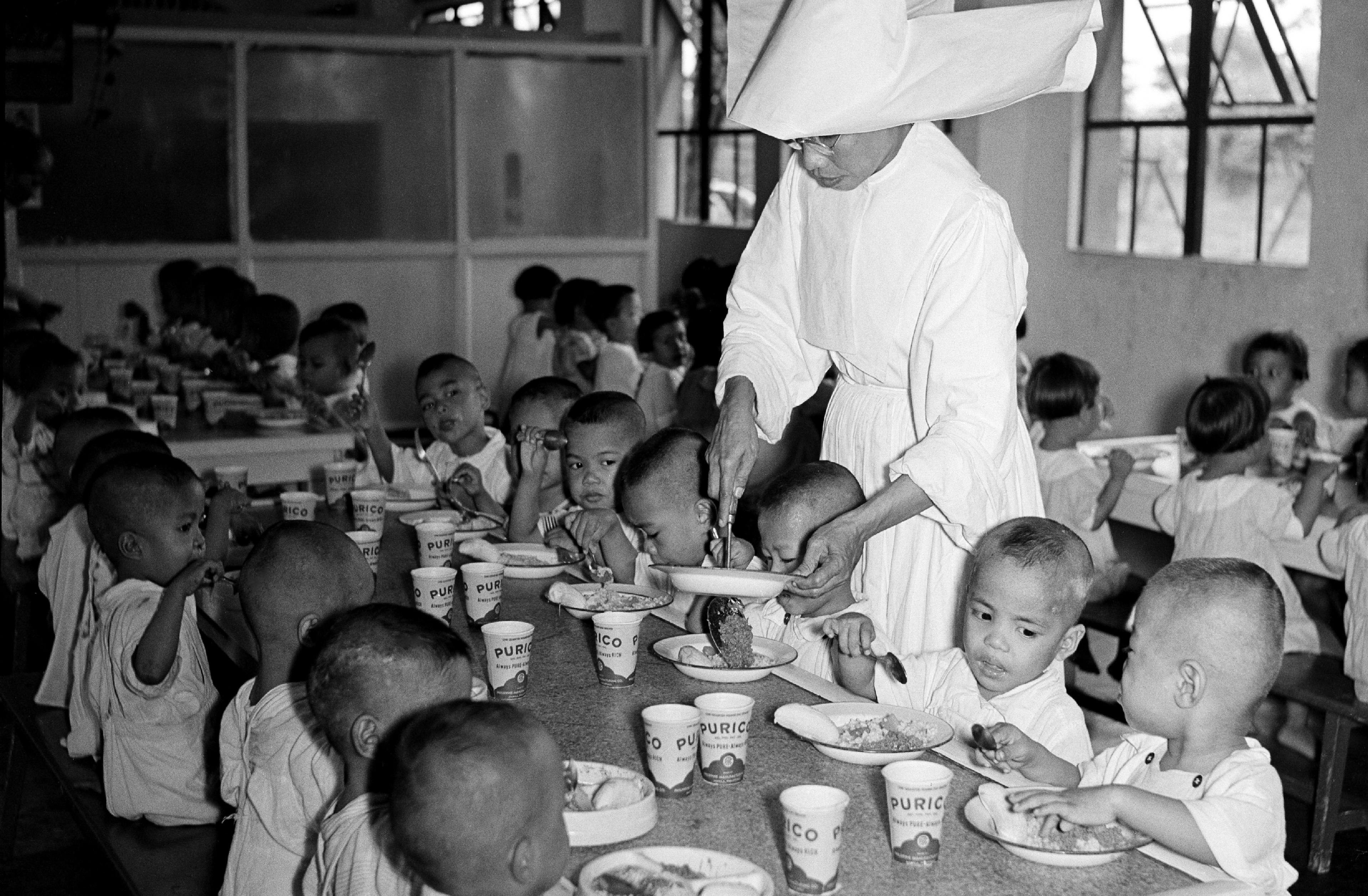 A nun serves children lunch, including a cup of UNICEF-supplied milk, in the White Cross nursery home in Manila, Philippines.