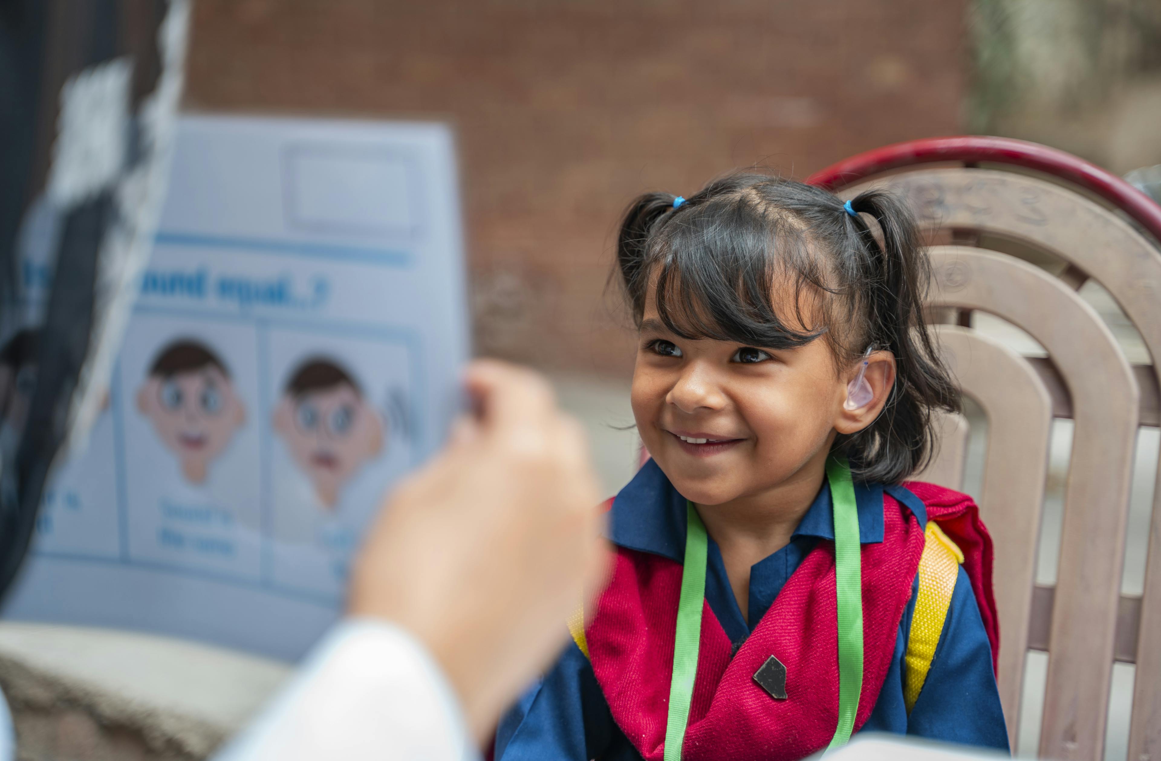 5-year-old Hoorain beams with joy as she tests her hearing aids under the guidance of an audiologist at the Government Deaf and Defective Girls High School in Rajgarh, Pakistan, on 28 March 2024.