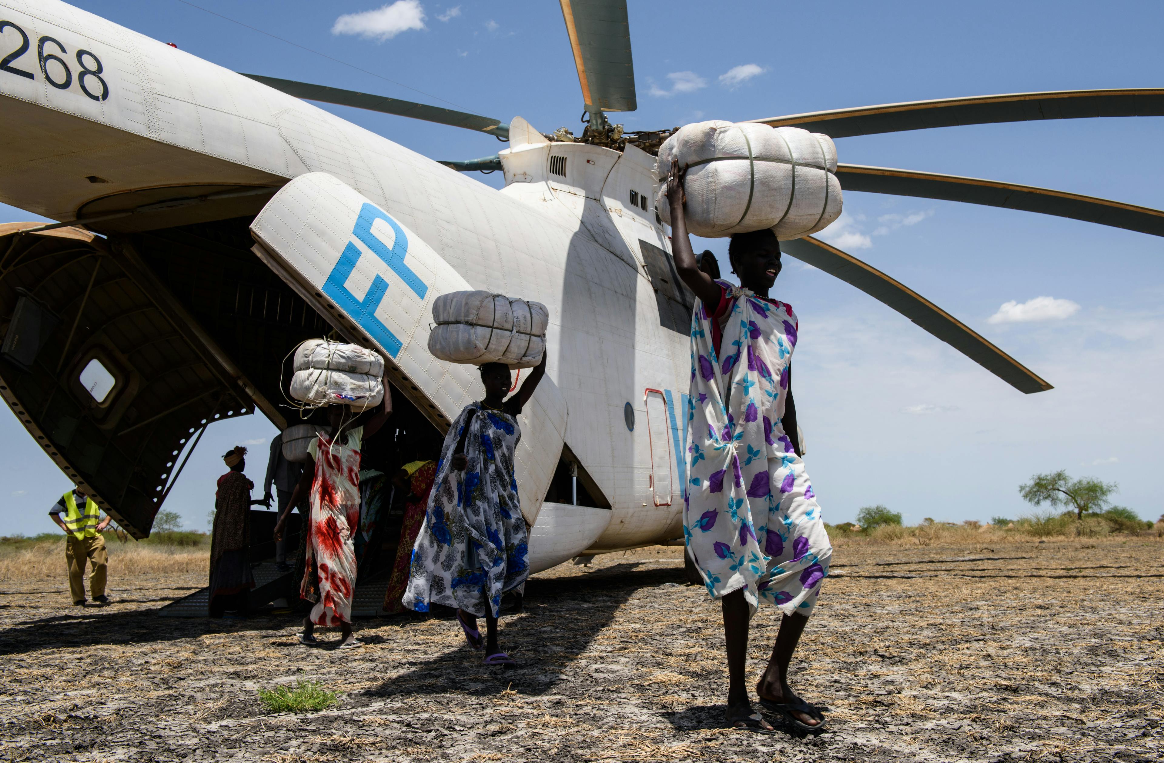 Porters carry bales of mosquito nets from a helicopter during a Rapid Response Mission in the village of Aburoc, South Sudan.