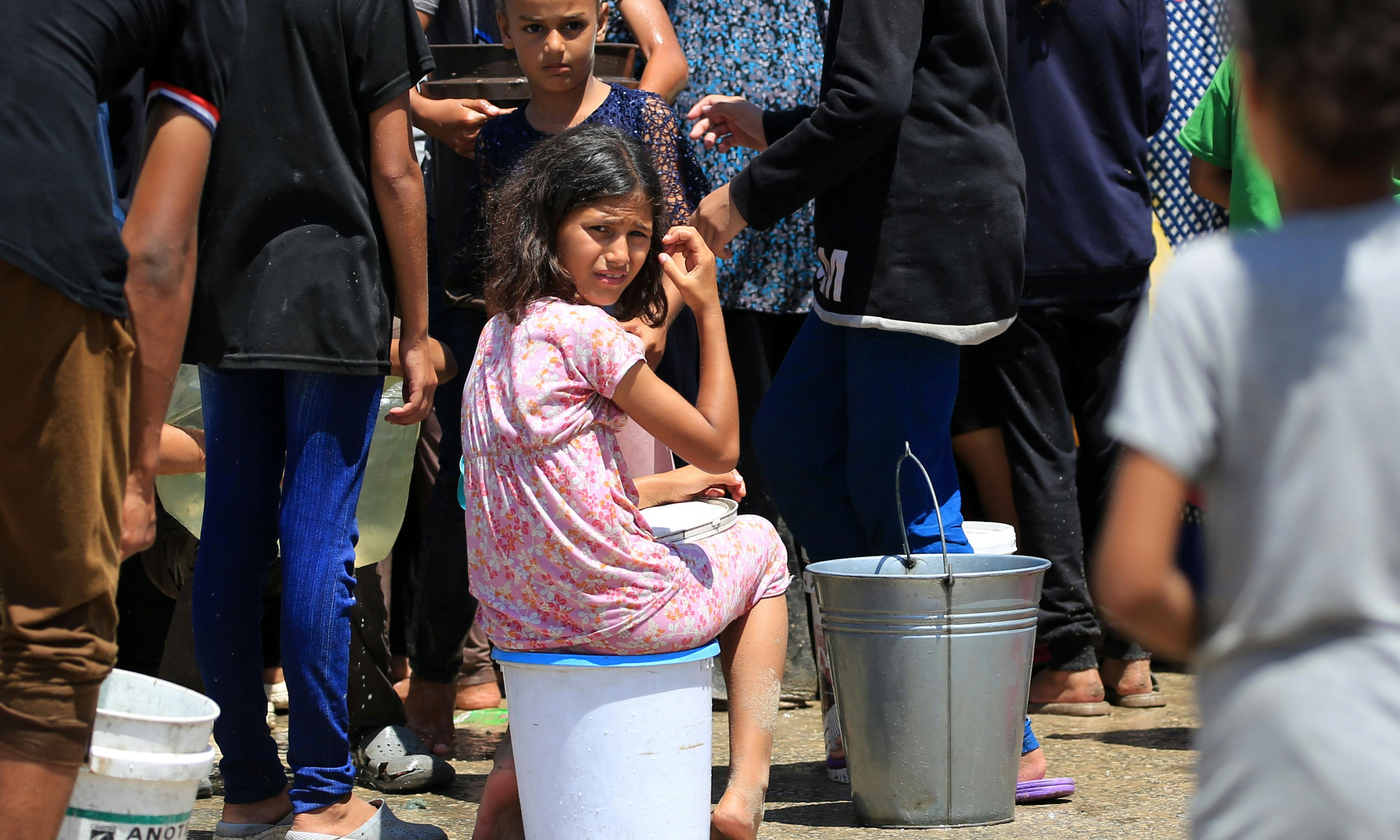 Children and their families fetching water from a UNICEF-supported water tank in Deir al-Balah, in the Gaza Strip.