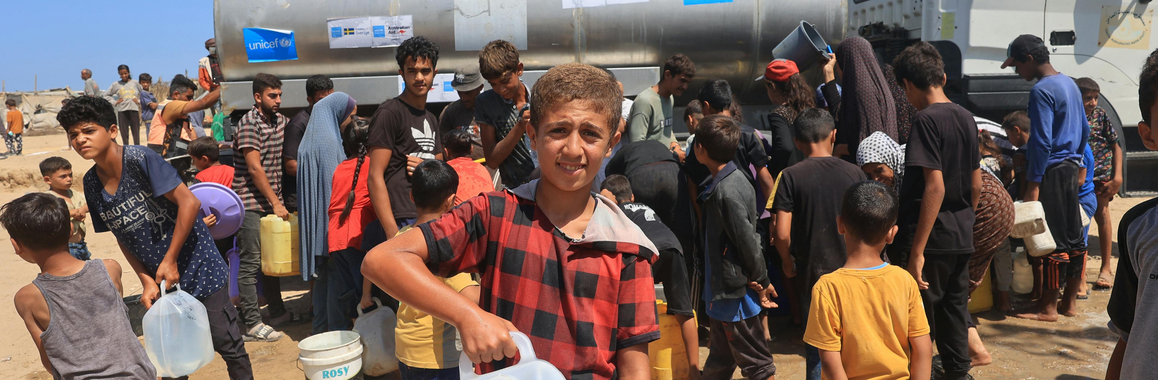 Youssef, 13-year-old, holding a Jerrycan after he filled it from a UNICEF-supported water tank in Deir al-Balah, in the Gaza Strip