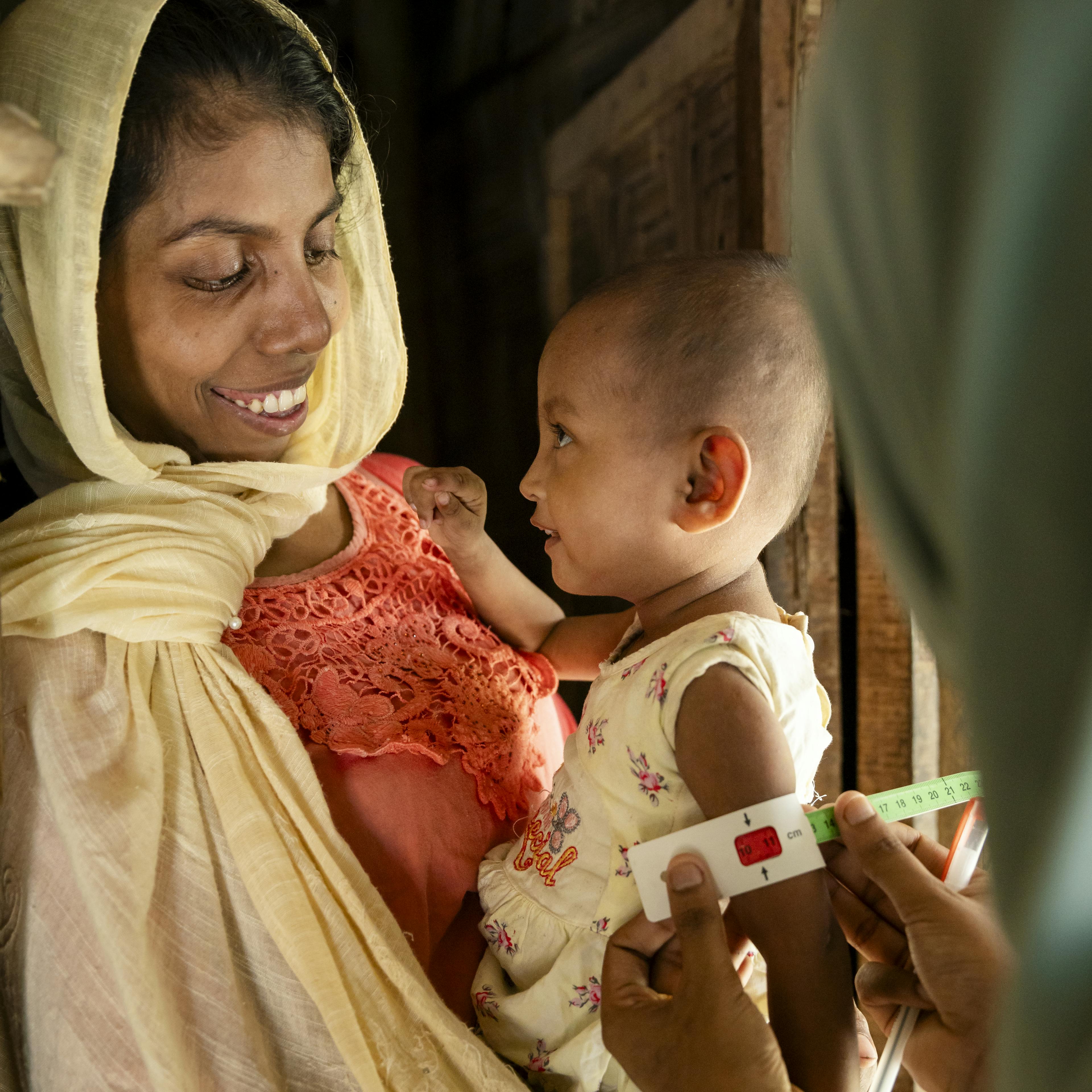 Rohingya community nutrition volunteer Taslima provides nutrition counselling for 2-year-old Sofiba at a Rohingya refugee camp in Bangladesh.