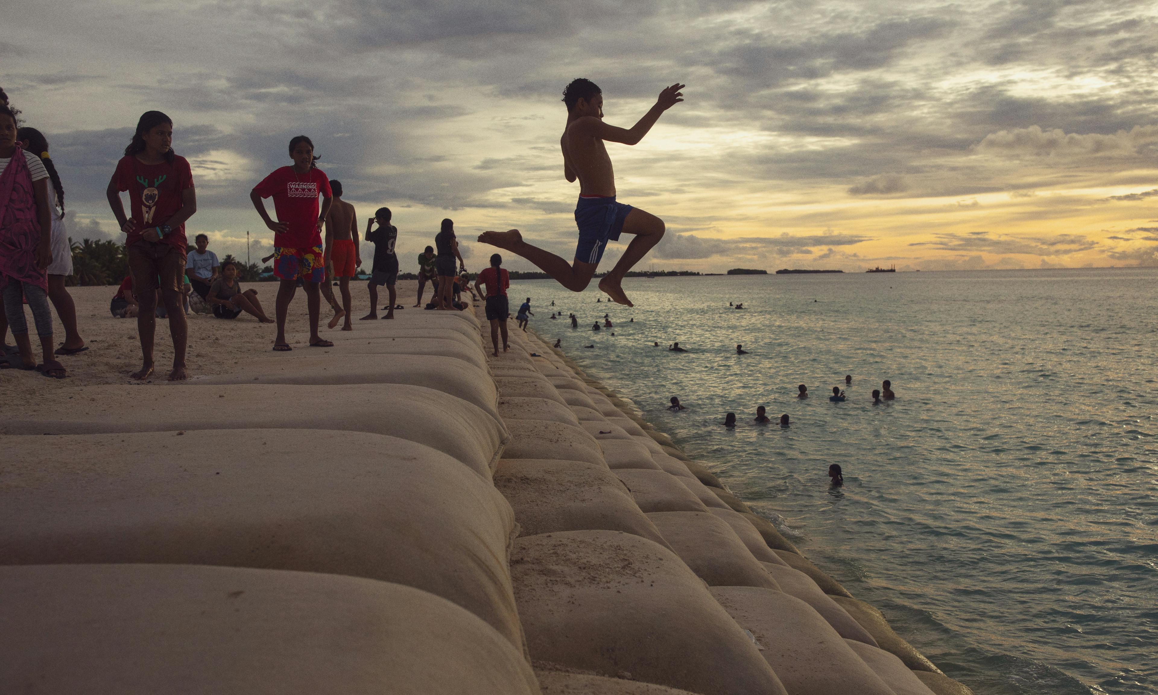 12-year-old Liveti jumps from a sandbag staircase at The Reclaimed Land into the sea in Tuvalu.