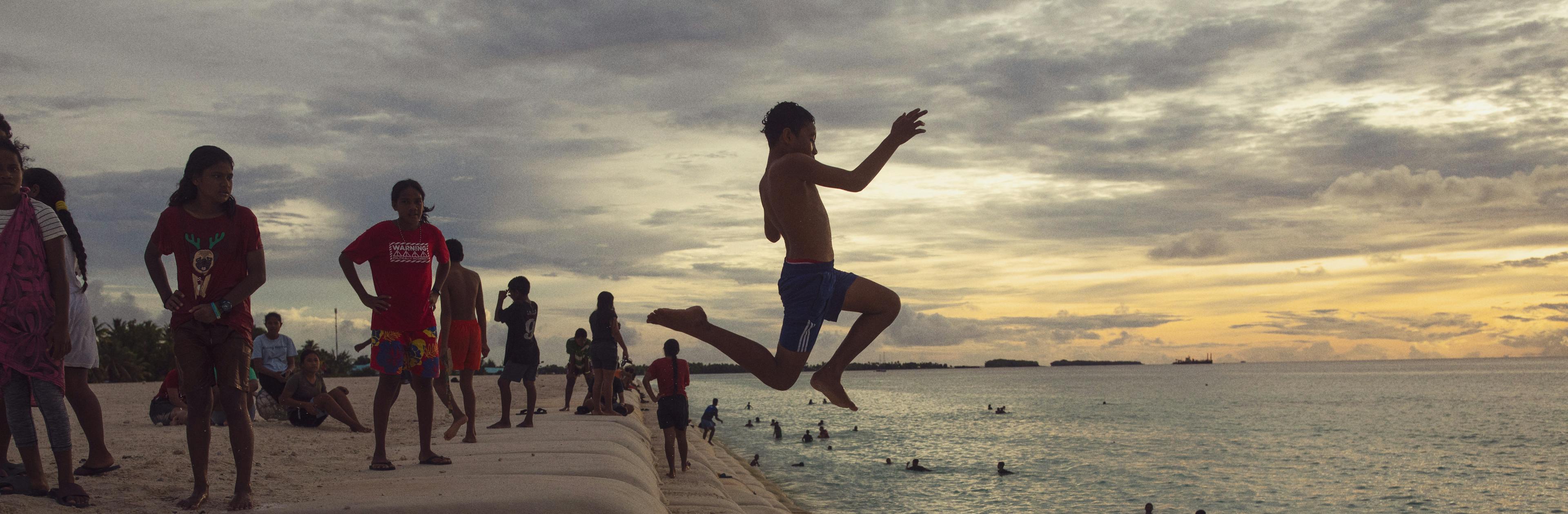 12-year-old Liveti jumps from a sandbag staircase at The Reclaimed Land into the sea in Tuvalu.