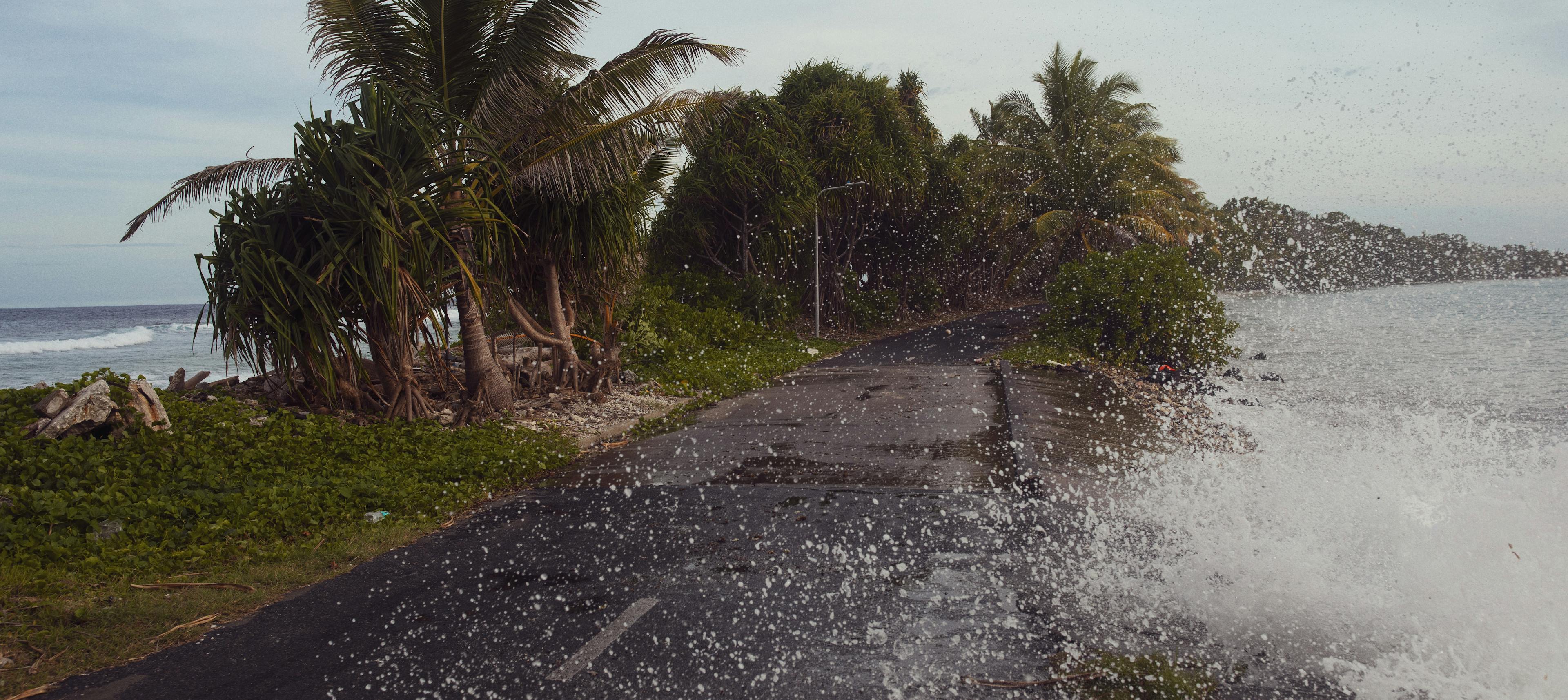 Waves crash against a road by Tuvalu's shoreline.