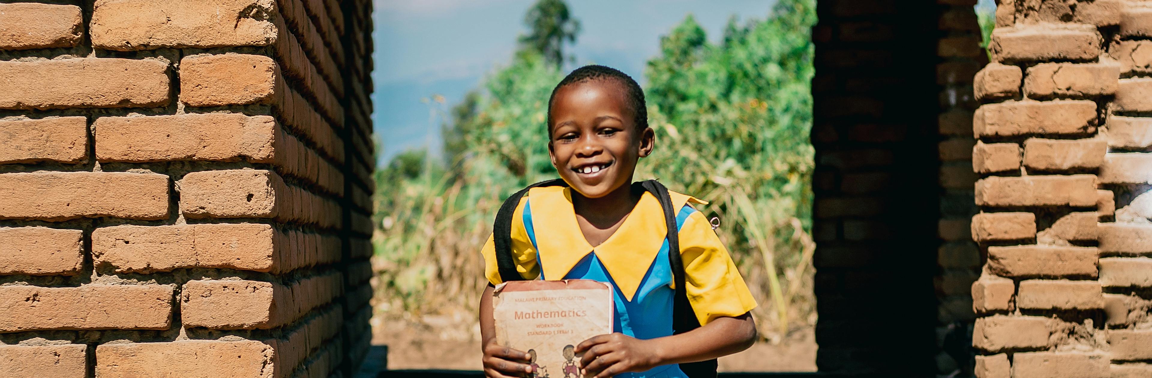 5-year-old Happiness Solomon, running while carrying her school bag and notebook to Mpasa Primary School in Malawi.