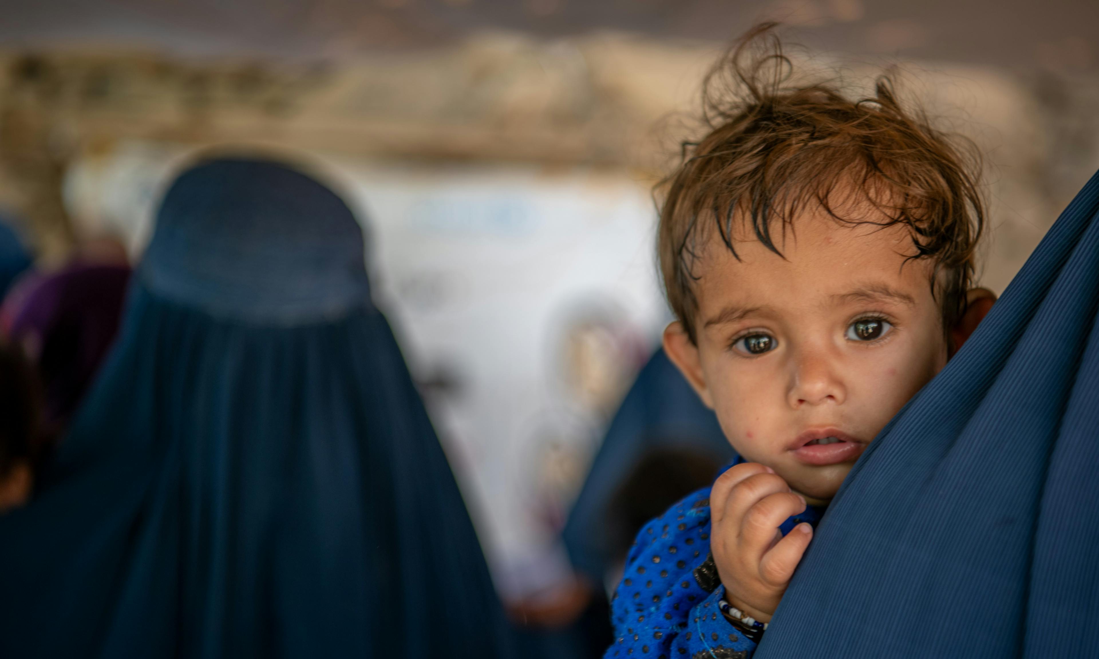 A little boy waits in his mother's arms at a UNICEF-supported mobile health and nutrition team in Nari District, Kunar Province, Afghanistan.