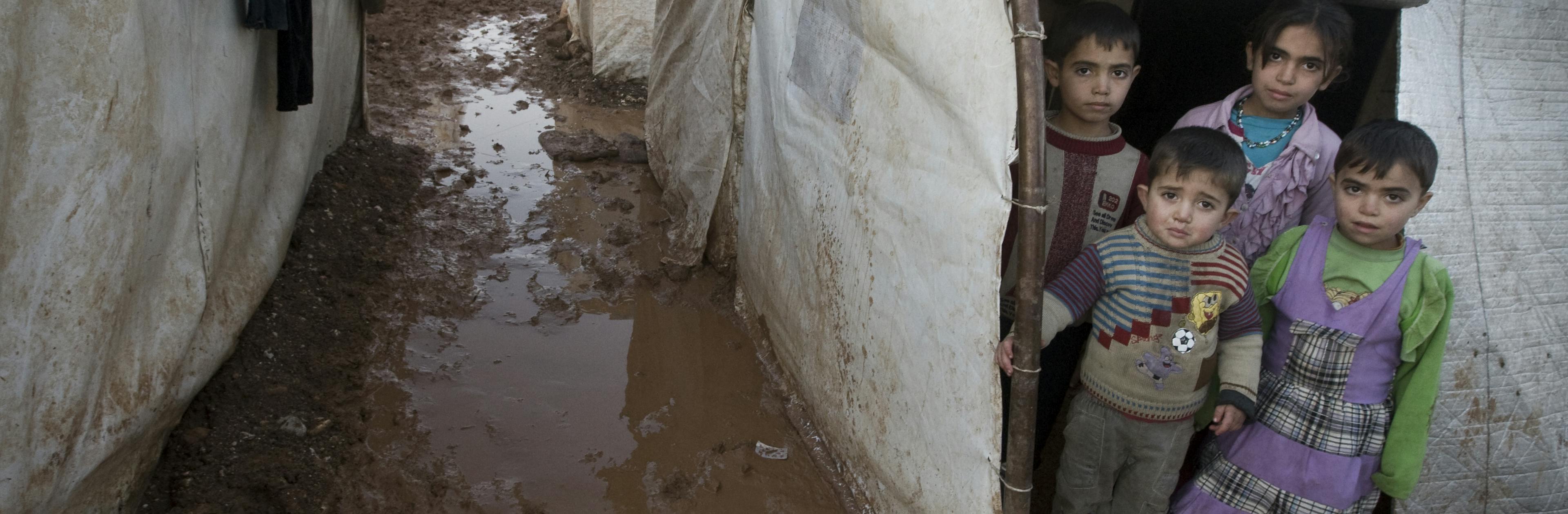 Children stand in the entryway of their tent shelter, in the Bab Al Salame camp for internally displaced persons in Syria