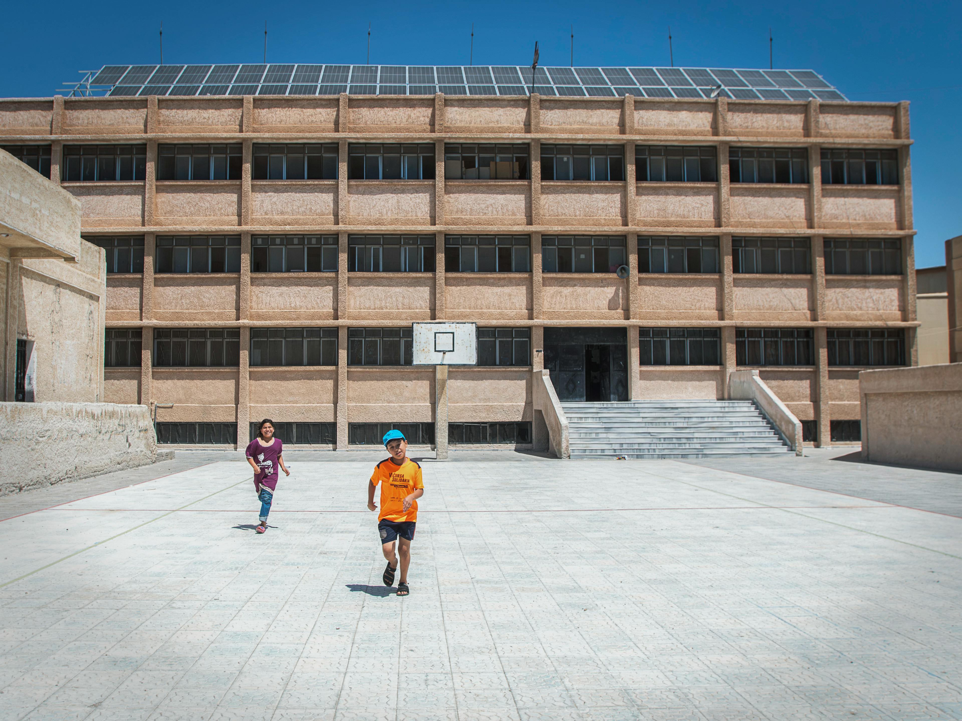 Narjes, 11, and Adam, 10, play in the schoolyard in Western gathering, Kisweh city.

UNICEF installed a solar power system to support drinking water pumping to the neighbourhood.