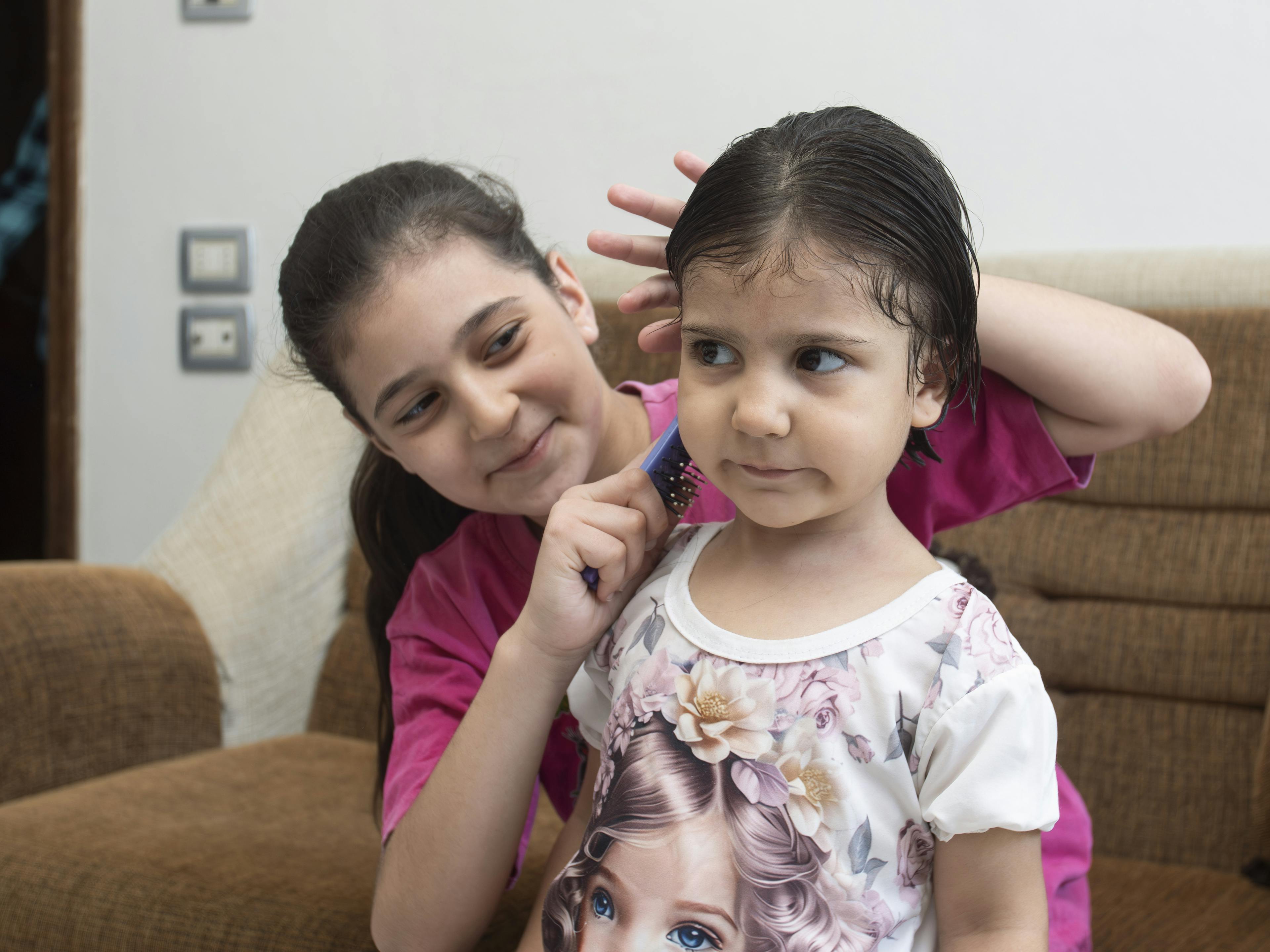 Masa, 11, combs her sister Shams’ hair at their home in Western gathering, Kisweh city, Rural Damascus, Syria, 25 July 2024.