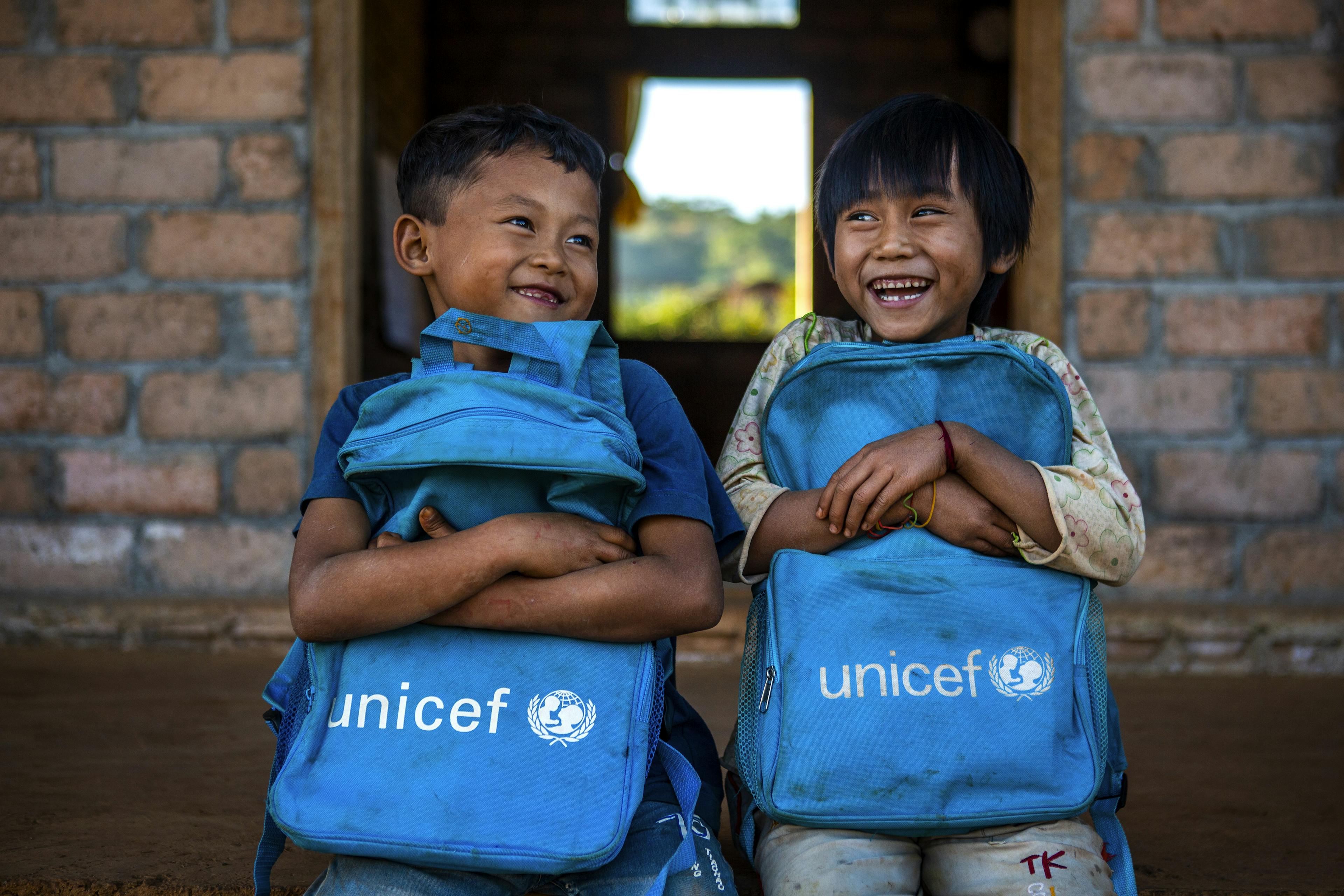 Aung Khin and Kham Li, both 7, hold UNICEF backpacks in front of their classroom at Pan lone hostel in Myanmar.