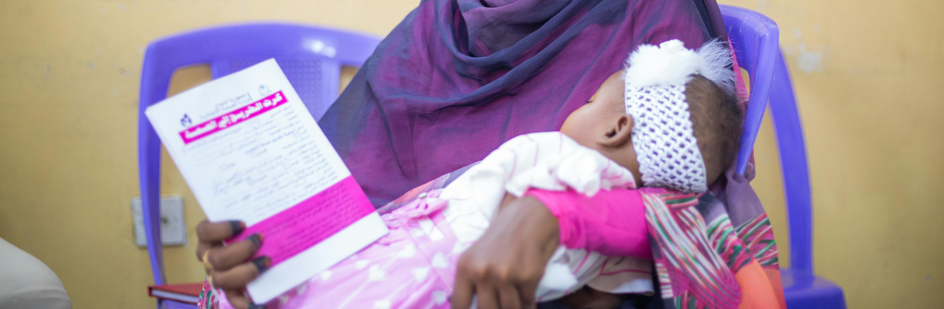 On 4 November 2024 in Gedaref, Sudan, 6-month-old Adan Mohammed is held by her mother, Romisa Mohammad Ali. Adan is the very first child to receive the malaria vaccine in Sudan.