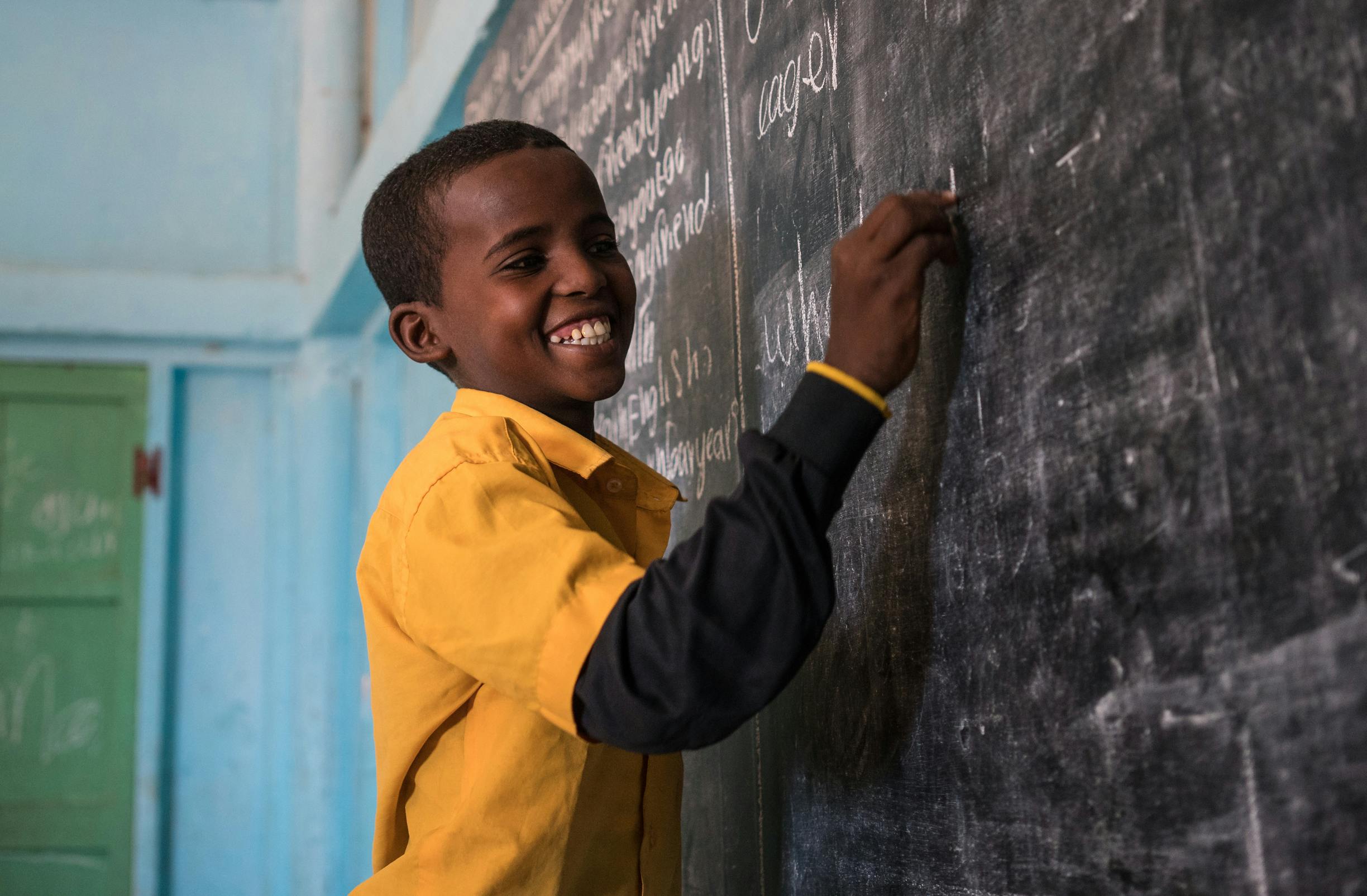 A student laughs as he writes the answers to questions on the chalkboard of his classroom in the UNICEF-supported Salaama primary school in Somalia.