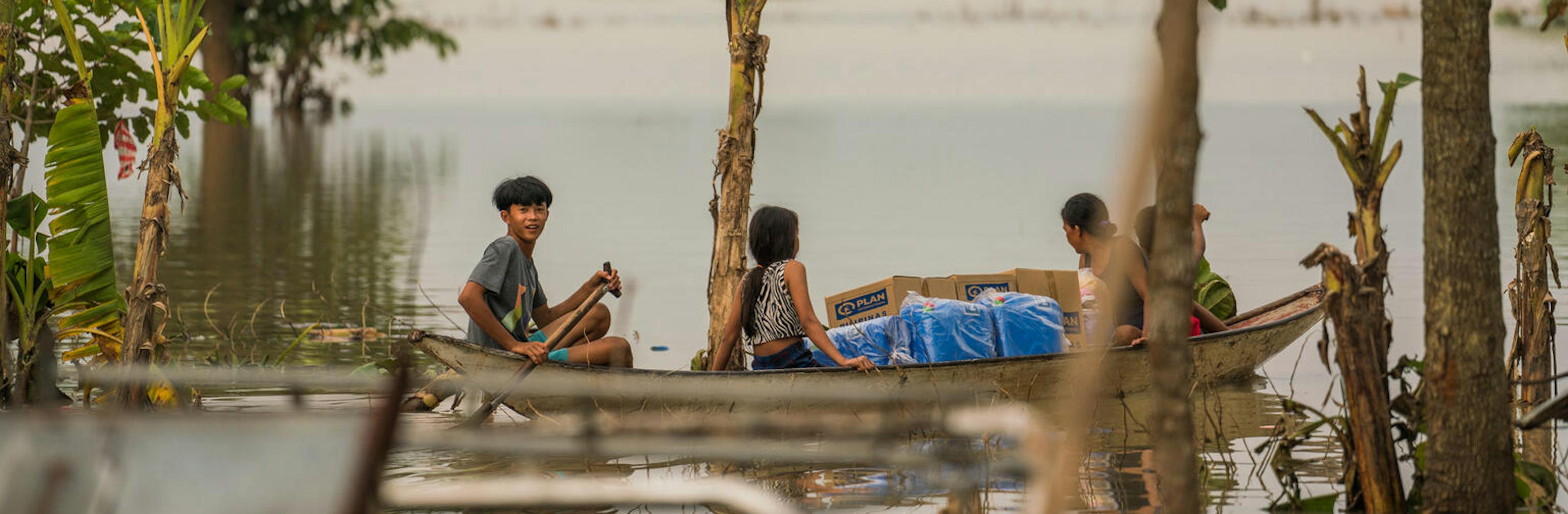 Children in the Philippines escape flood waters by boat while carrying hygiene kits distributed by UNICEF and partner  Plan International Philippines