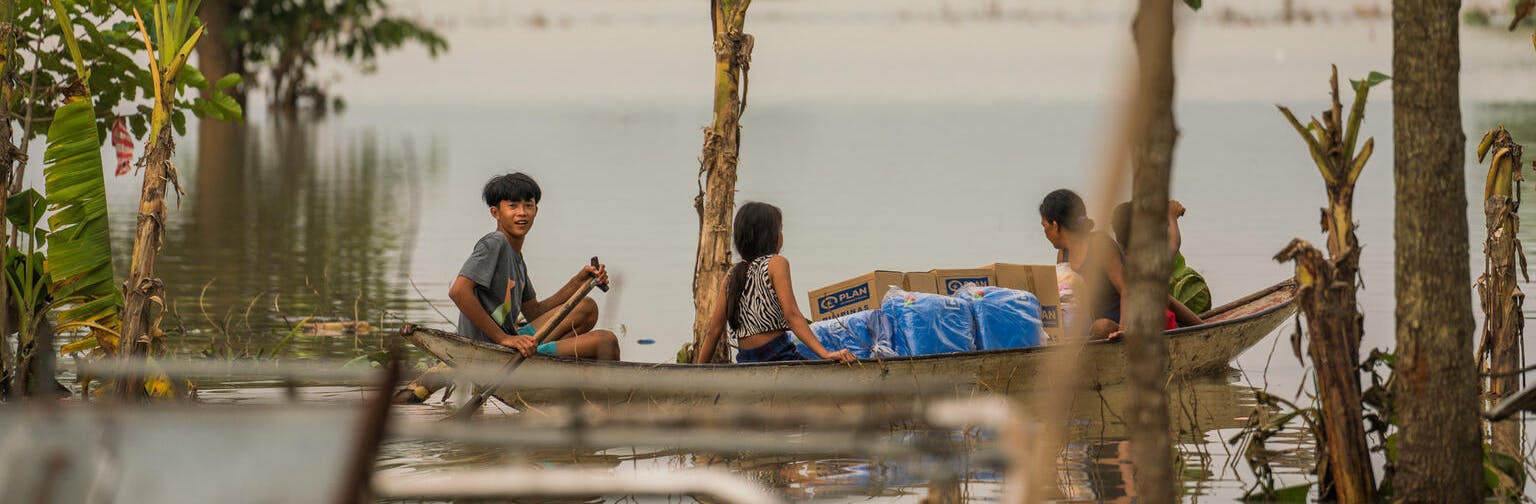 Children in the Philippines escape flood waters by boat while carrying hygiene kits distributed by UNICEF and partner Plan International Philippines