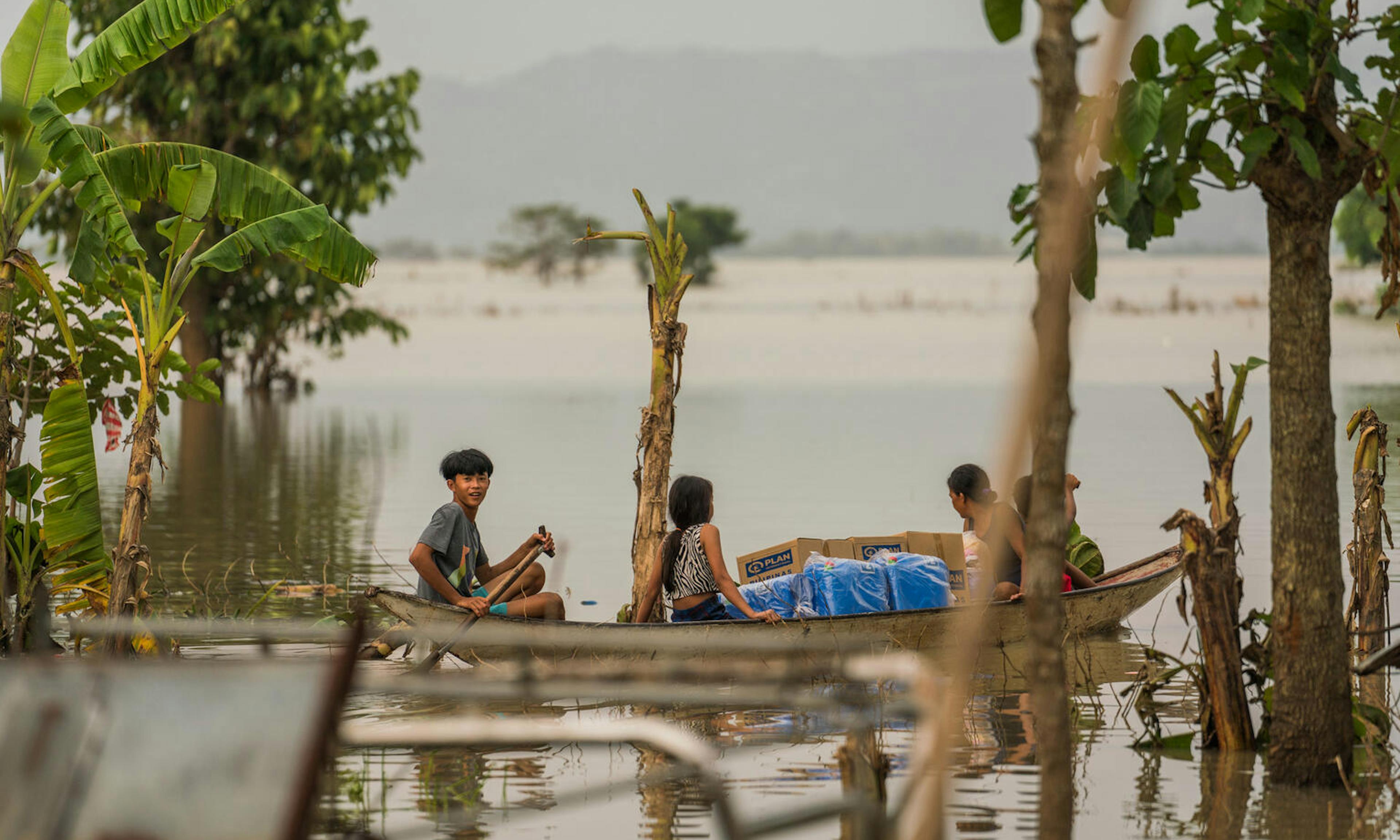 Children in the Philippines escape flood waters by boat while carrying hygiene kits distributed by UNICEF and partner  Plan International Philippines