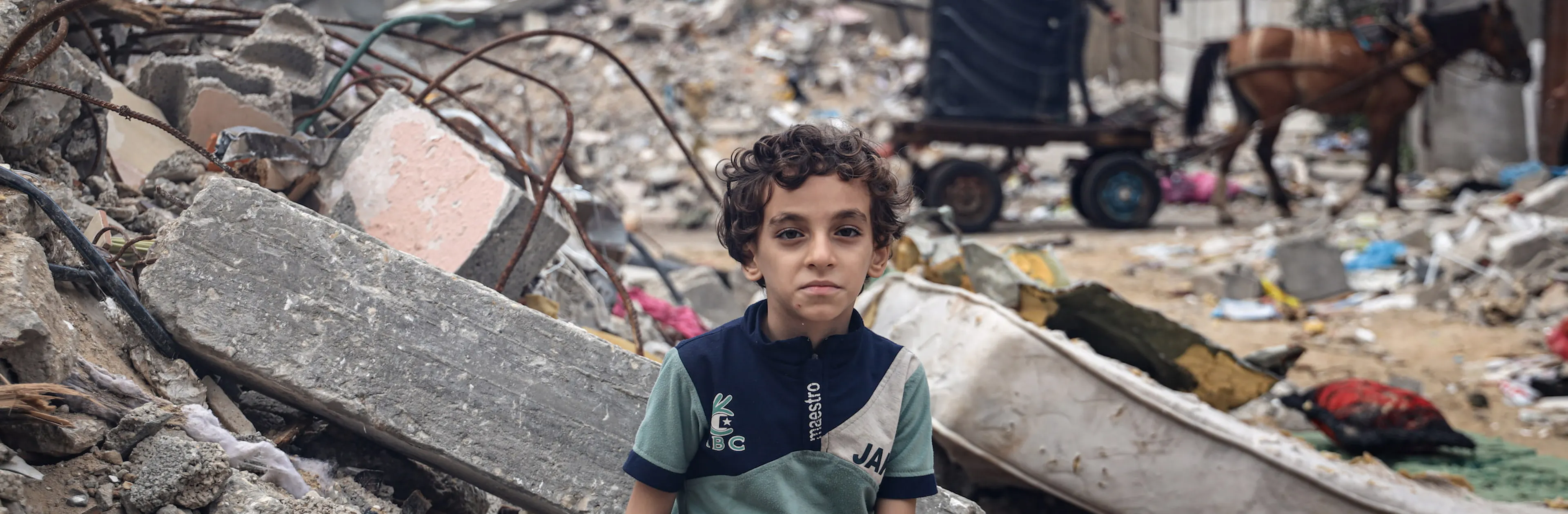 Mohammed Alattar, 8-year-old from Rafah City, sits on the rubble of his family's house, which was bombed in an Israeli airstrike.