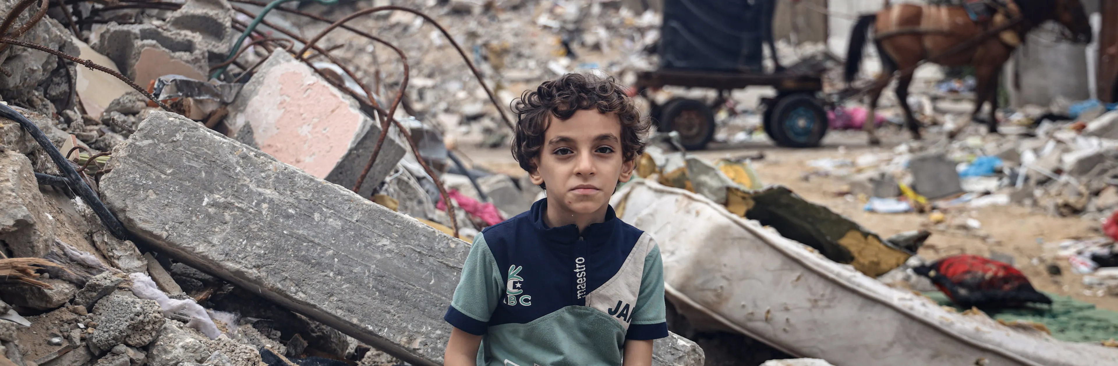 Mohammed Alattar, 8-year-old from Rafah City, sits on the rubble of his family's house, which was bombed in an Israeli airstrike.