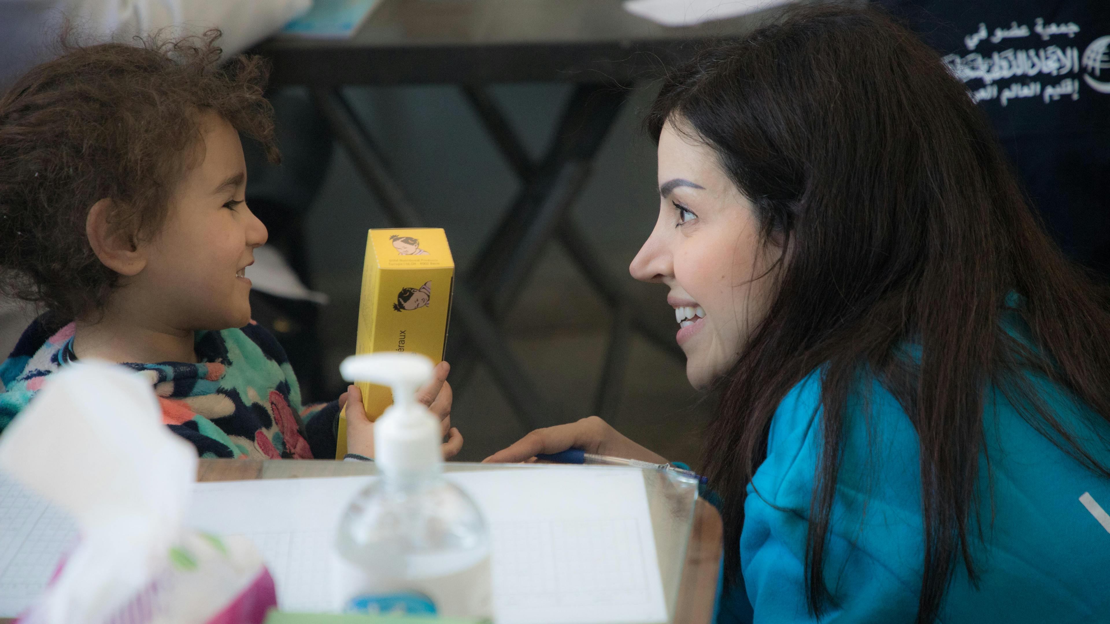 Five-year-old Huda has a friendly chat with a UNICEF staff member in the exam room of a UNICEF-supported clinic at a school in Lattakia, Syria.